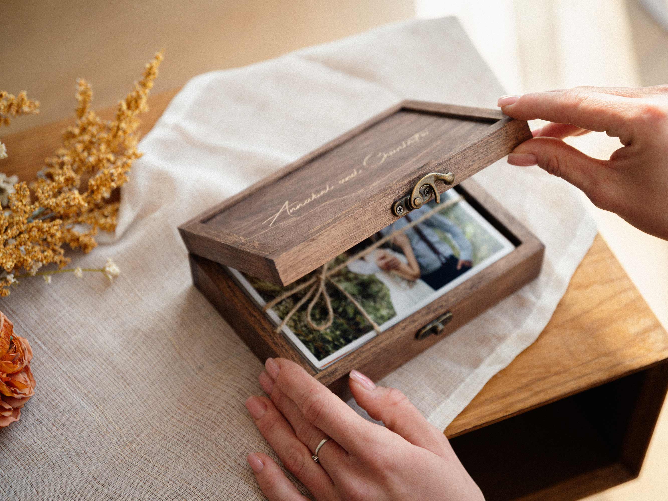 Hands opening Walnut Classic wooden photo box with printed wedding photos
