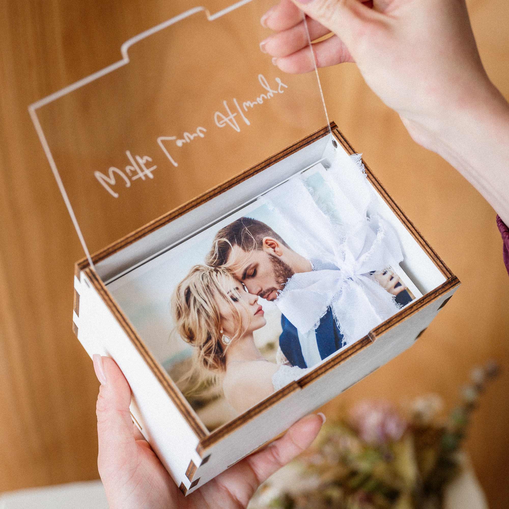 Hands opening white wooden photo box with personalized acrylic lid