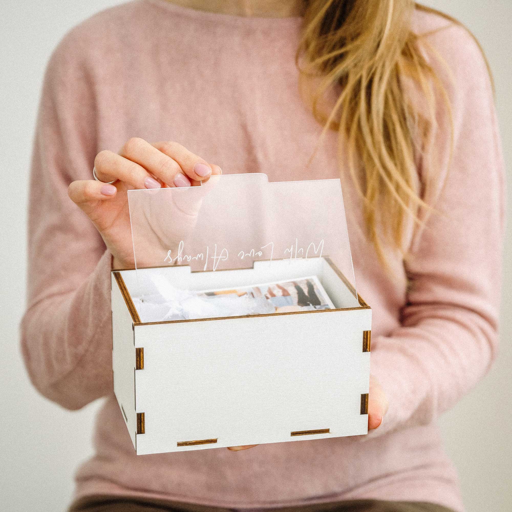 Woman holding white wooden wedding photo box with acrylic lid and prints
