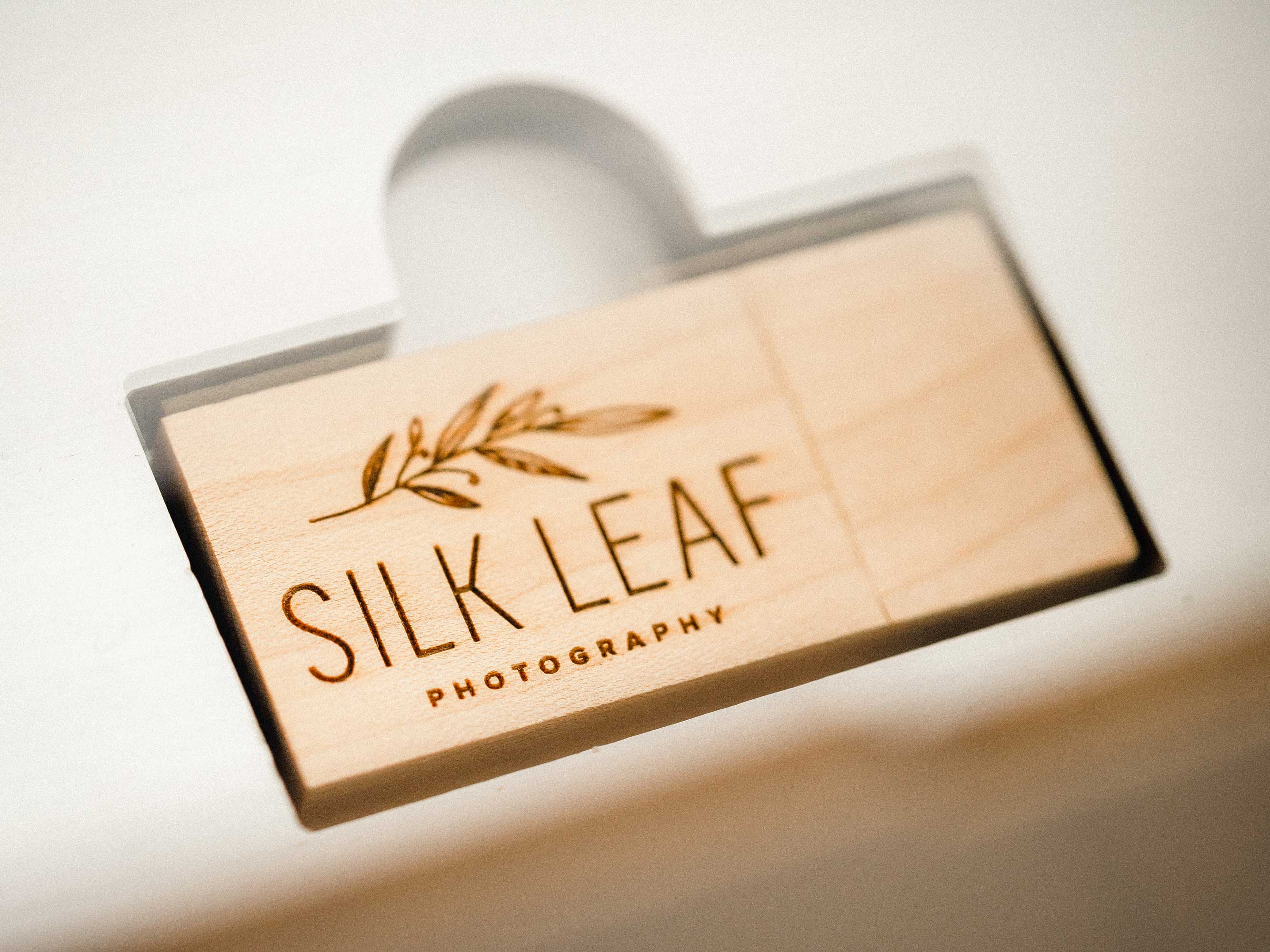 Closed white wooden photo box with engraved acrylic lid and photographer logo