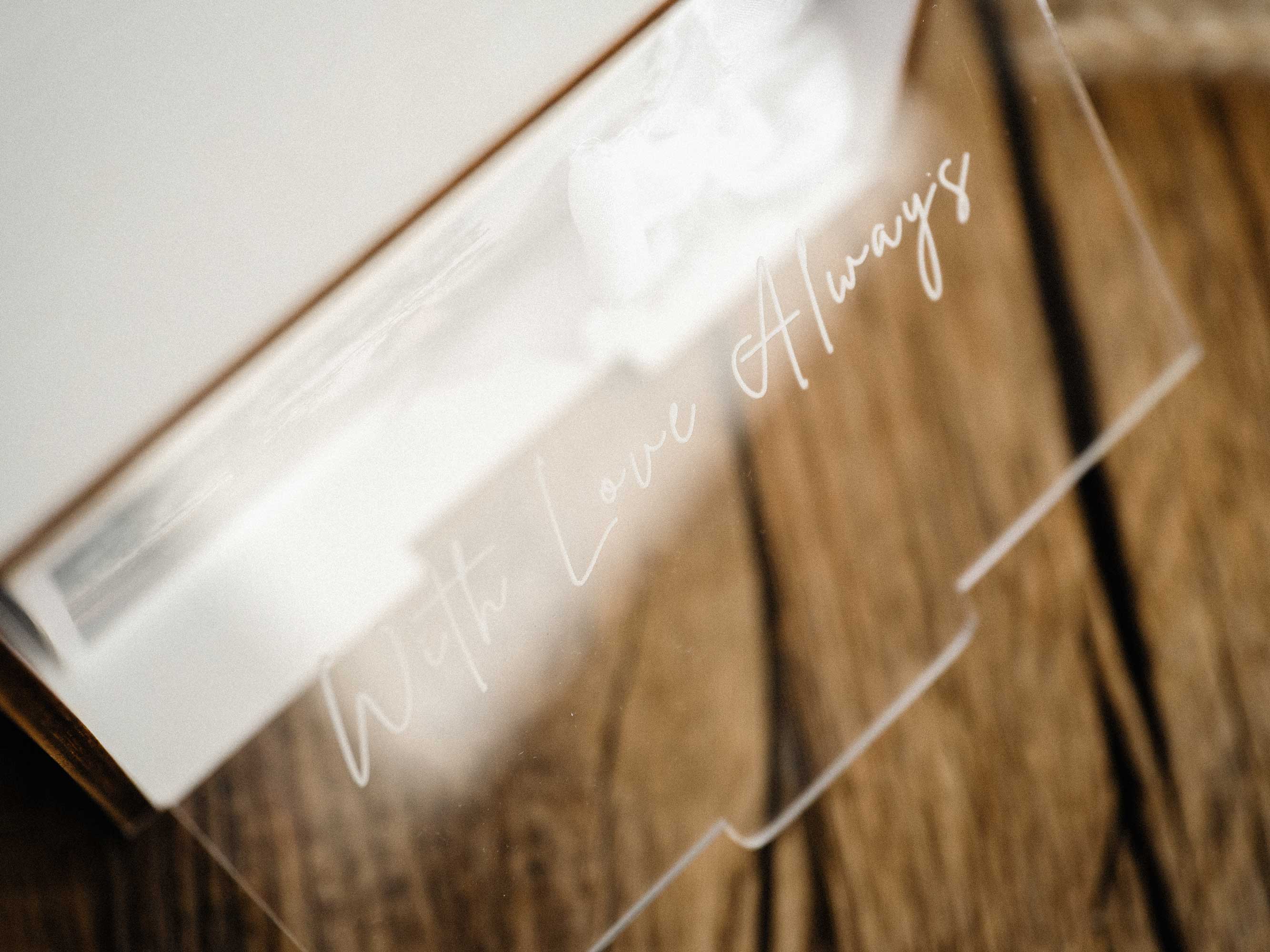 Close-up of engraved acrylic lid on white wooden wedding photo box