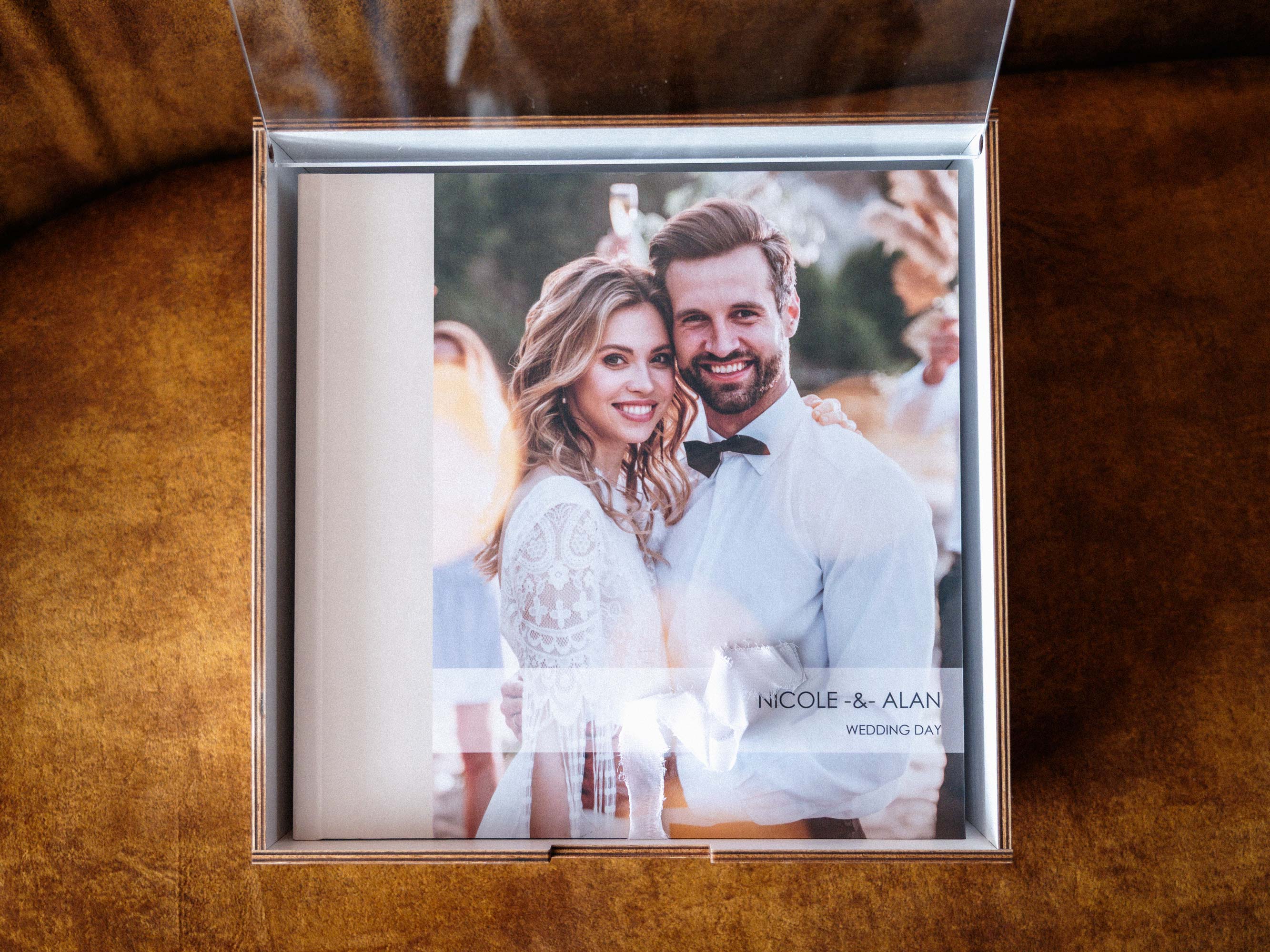 Top view of white wedding album box with photo album inside and acrylic lid open