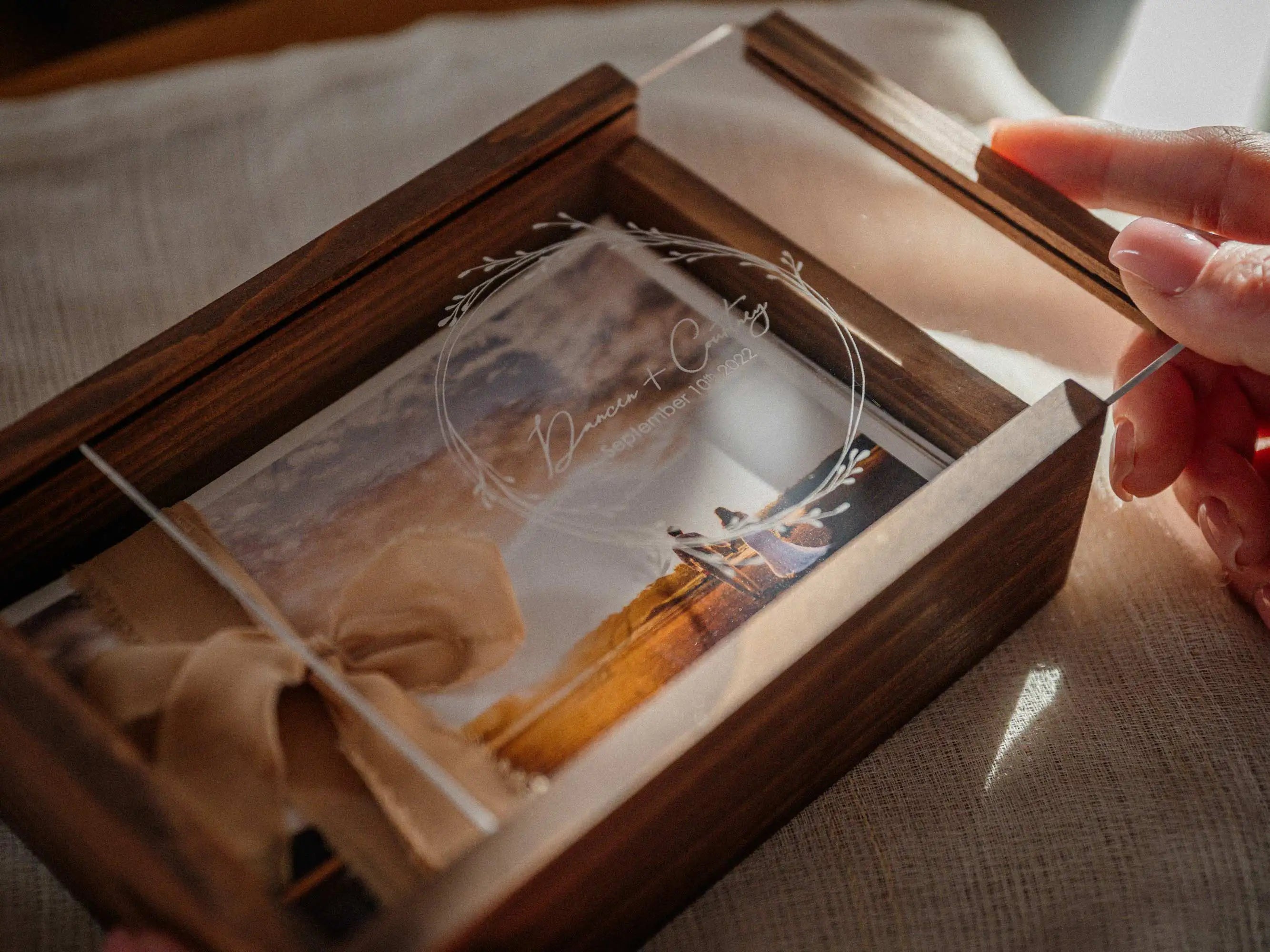 Hands opening walnut wooden photo box with personalized acrylic lid