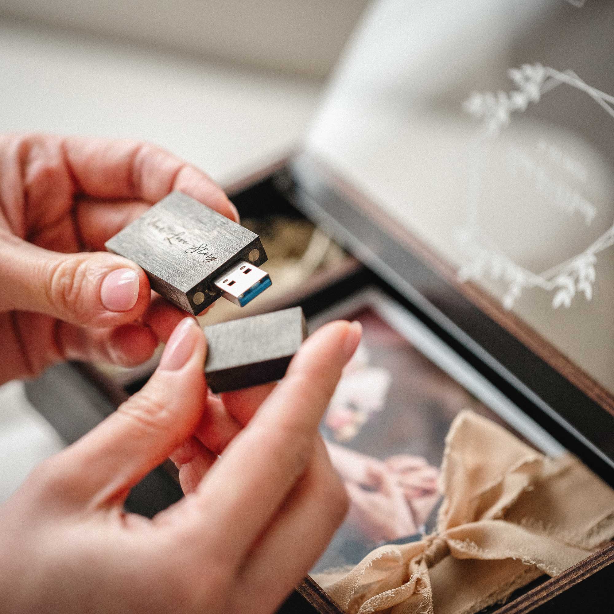 Wooden USB flash drive for black wedding photo box held in hands
