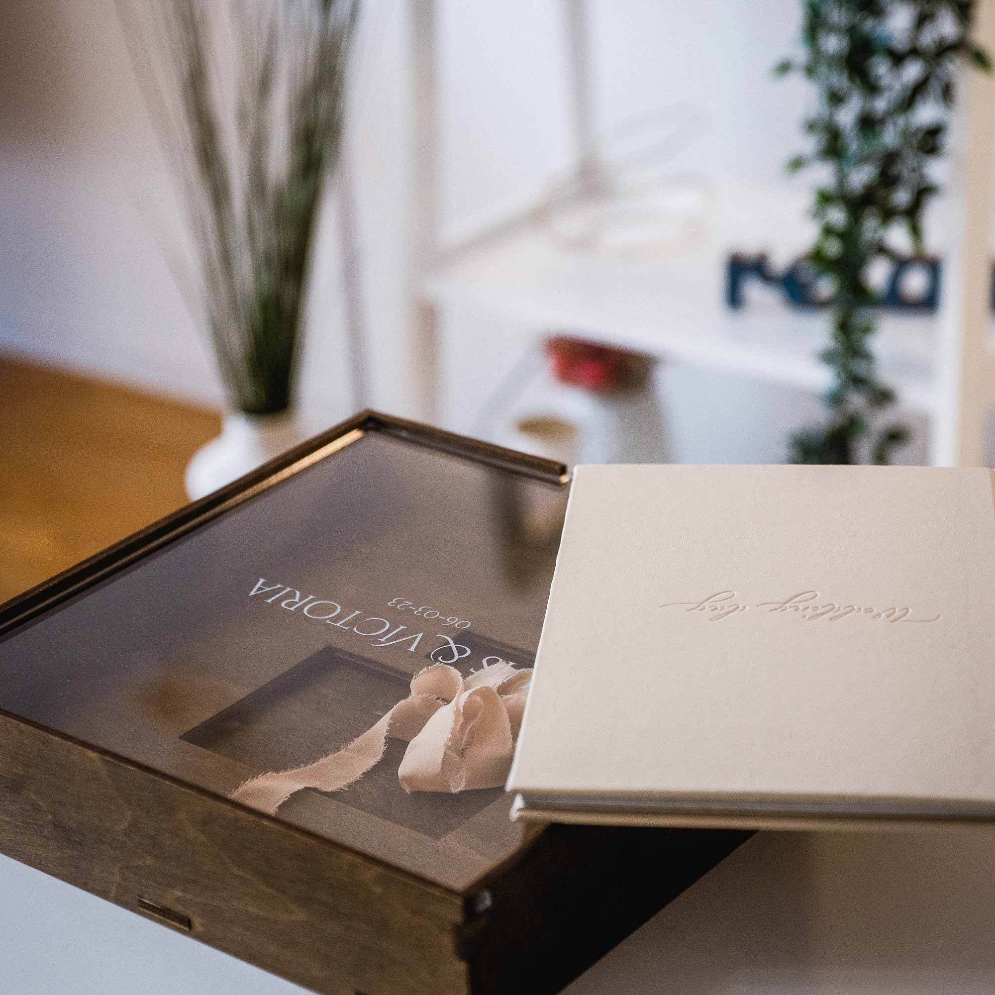 Beige wedding album with embossed cover beside wooden wedding album box