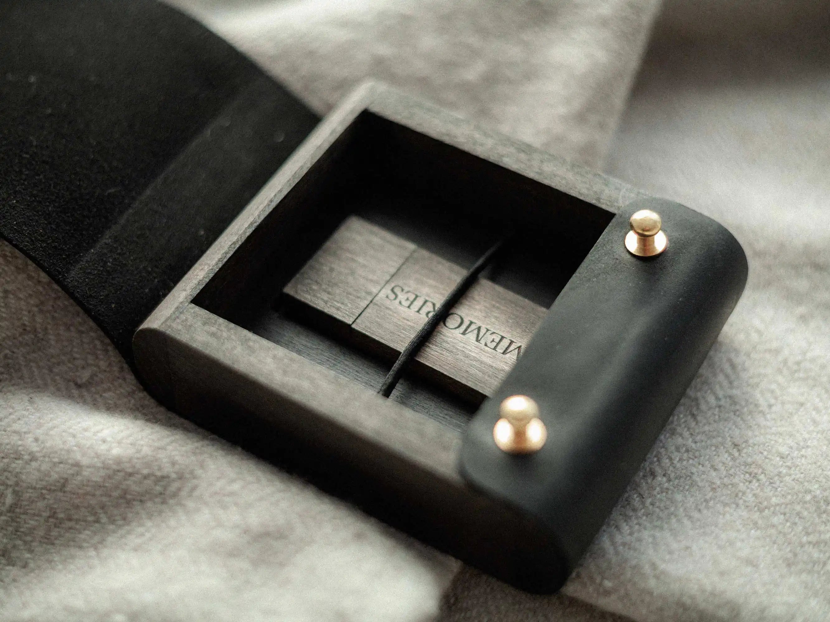 Open black leather USB box with wooden USB drive inside, lifestyle on soft fabric