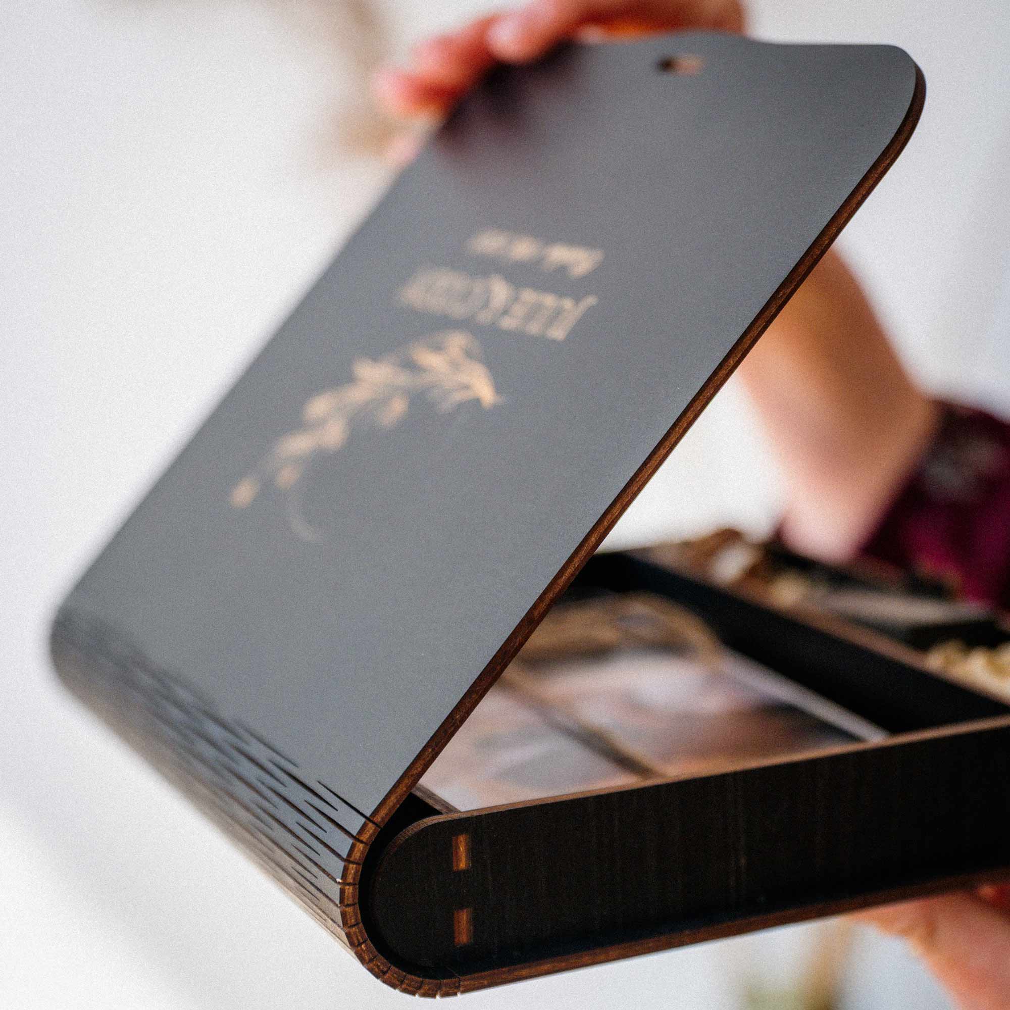 Side view of black personalized photo box with curved lid and engraved design