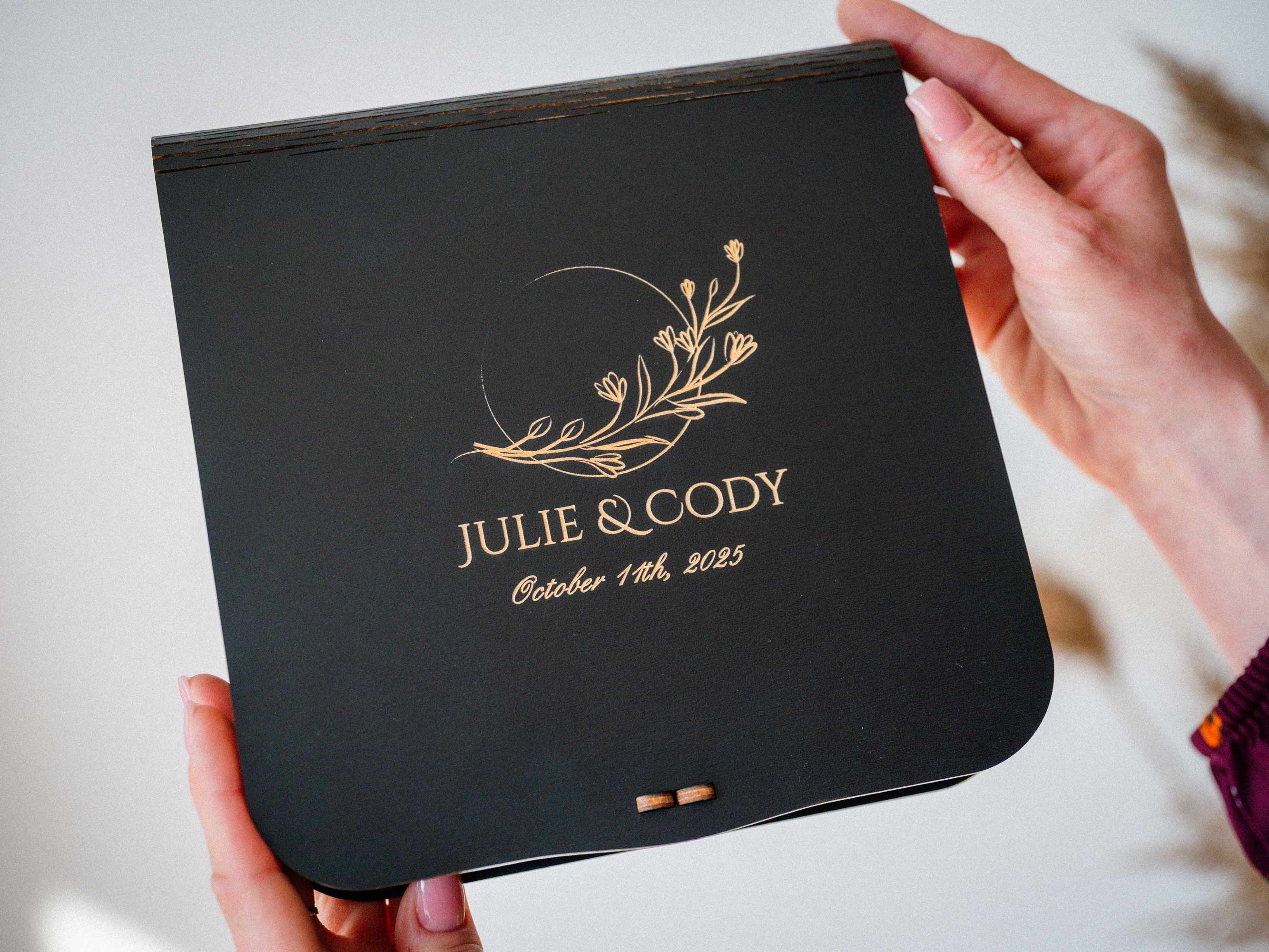 Black personalized wooden photo box with USB for wedding prints, engraved keepsake box held in hands