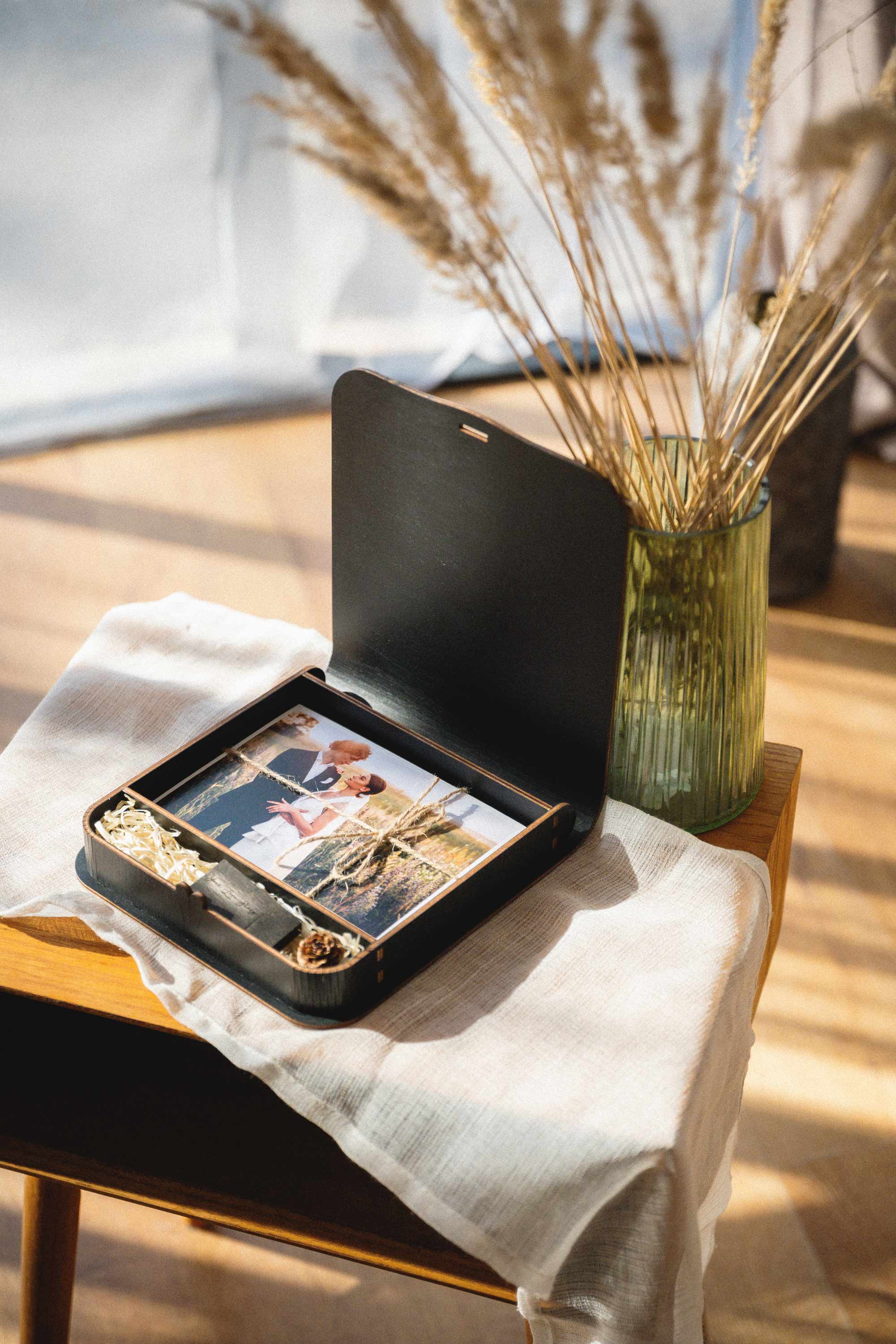 Black keepsake photo box with USB and wedding prints styled on a table