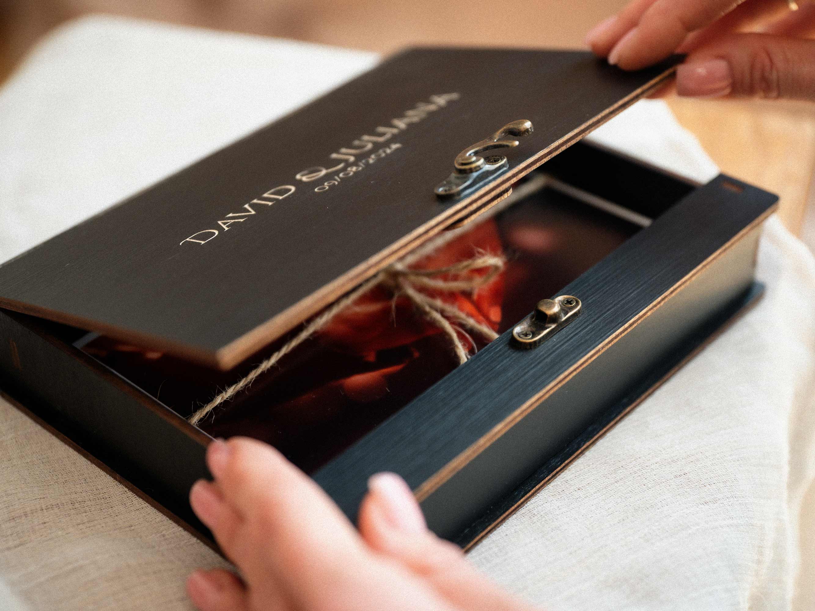 Open black wedding photo box showing photo prints inside