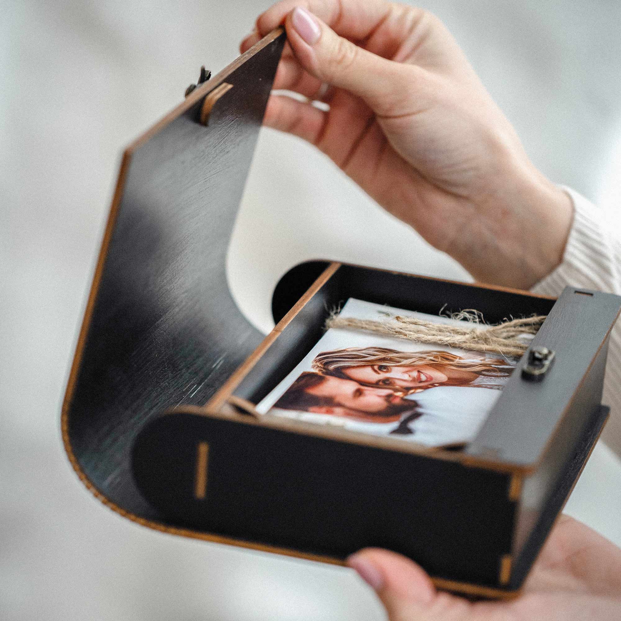 Open black wooden photo box reveal with photo prints inside, curved lid, client keepsake presentation
