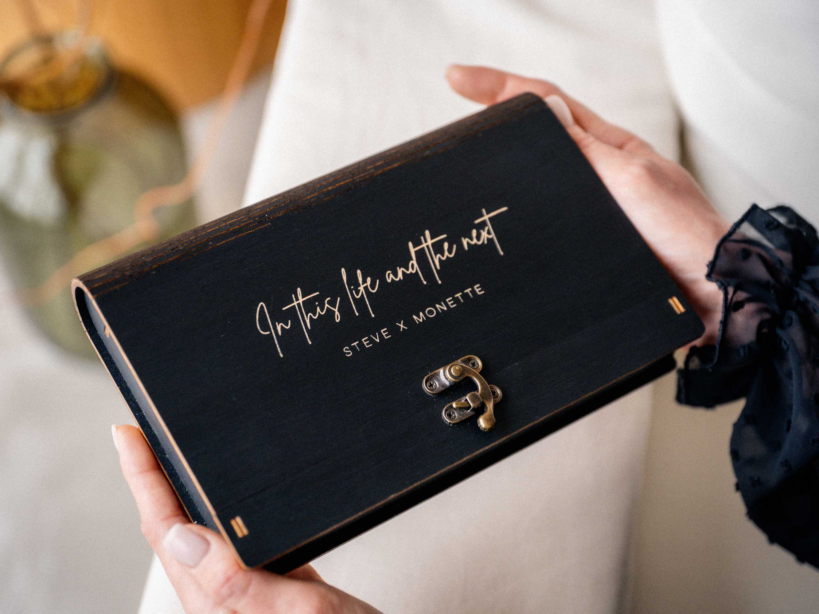 Closed black wooden photo box with custom gold engraving for wedding clients