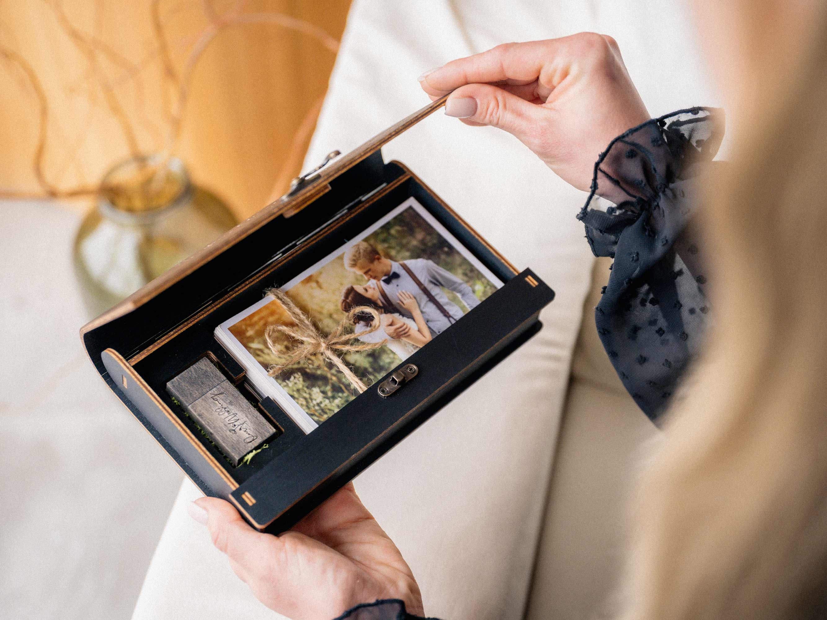 Open black photo box with USB compartment and printed wedding photos inside