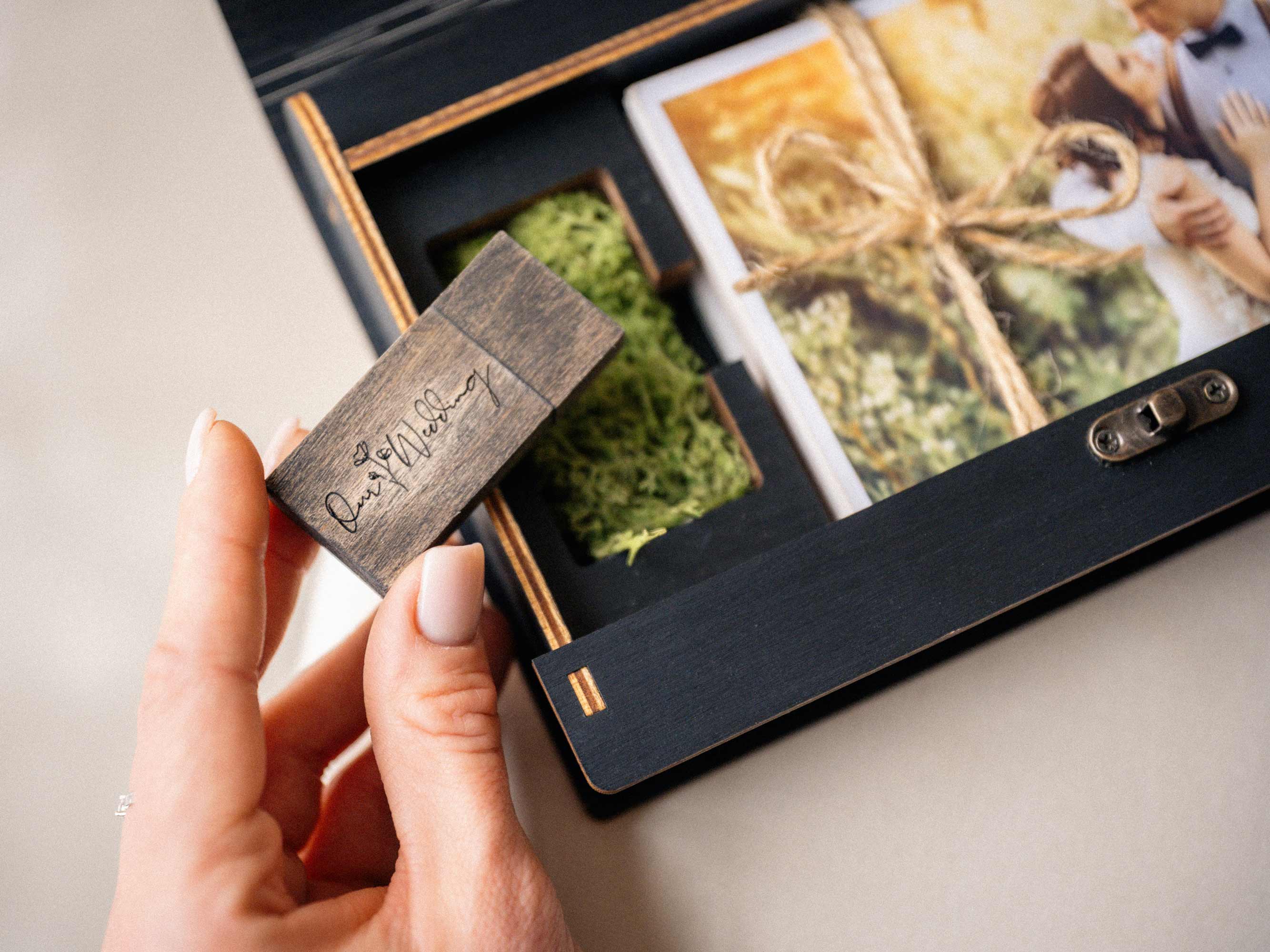 Wooden USB flash drive inside black photo box with wedding photo prints