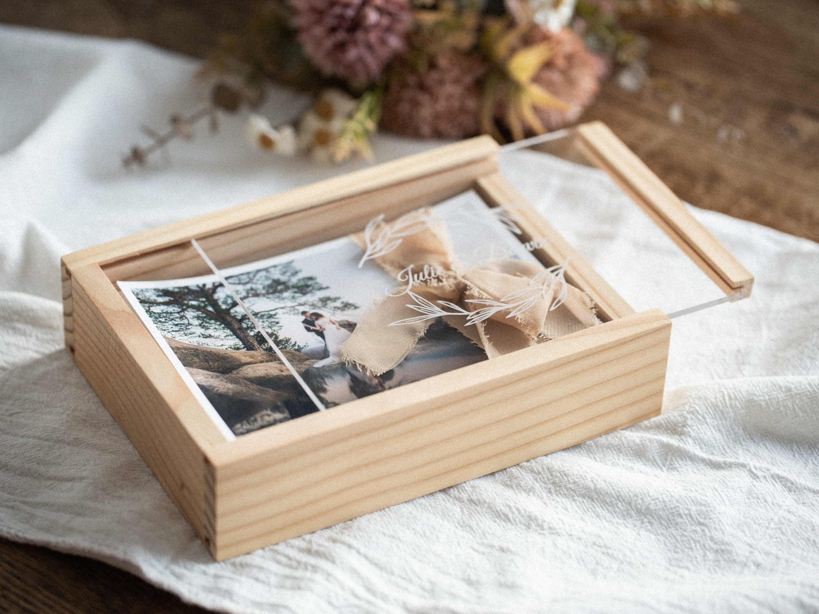 Angled side view of maple wooden box with clear acrylic lid and ribbon bow, wood grain detail.
