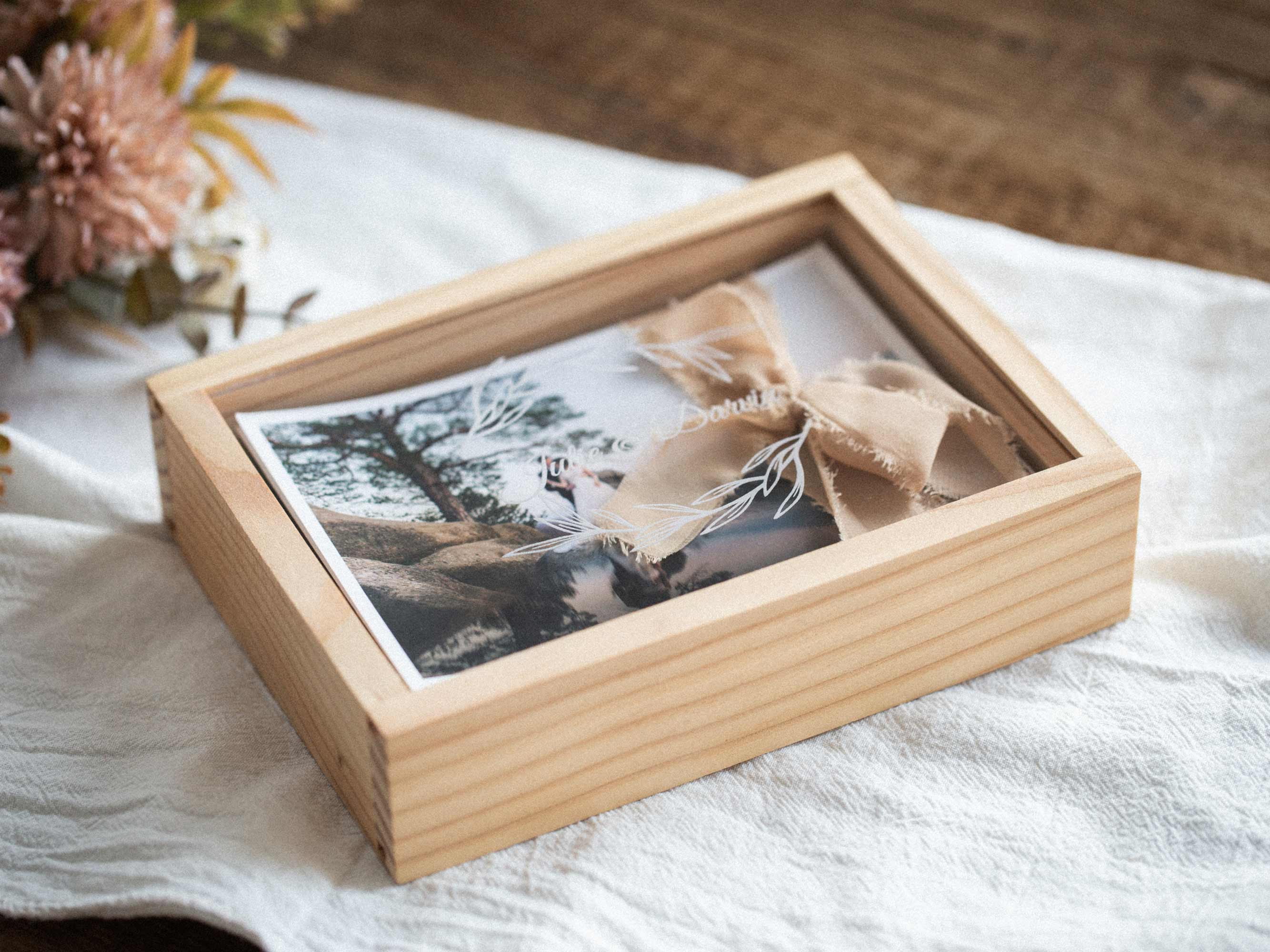 Maple wooden photo box closed with linen ribbon bow, lifestyle styling with dried flowers.
