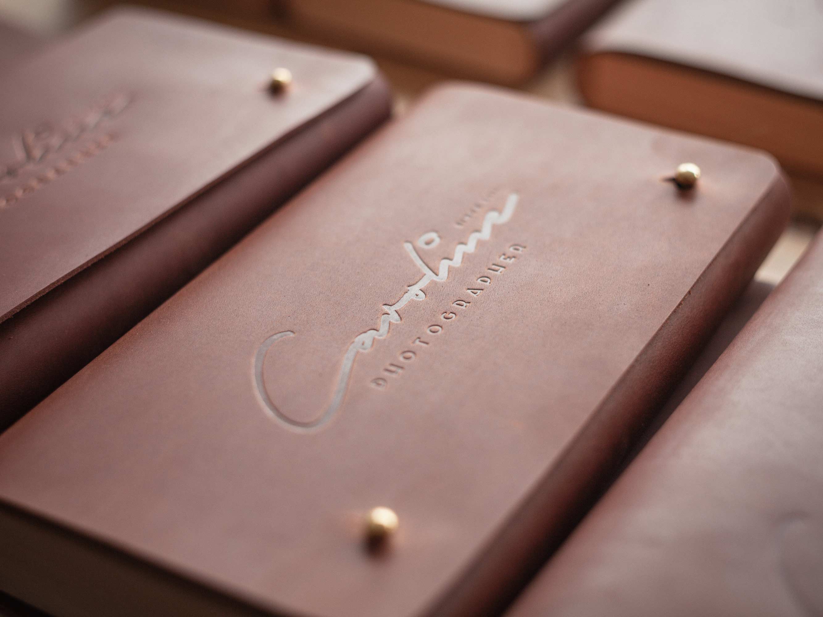 Debossed photographer logo on brown leather flap, premium packaging for photo clients.