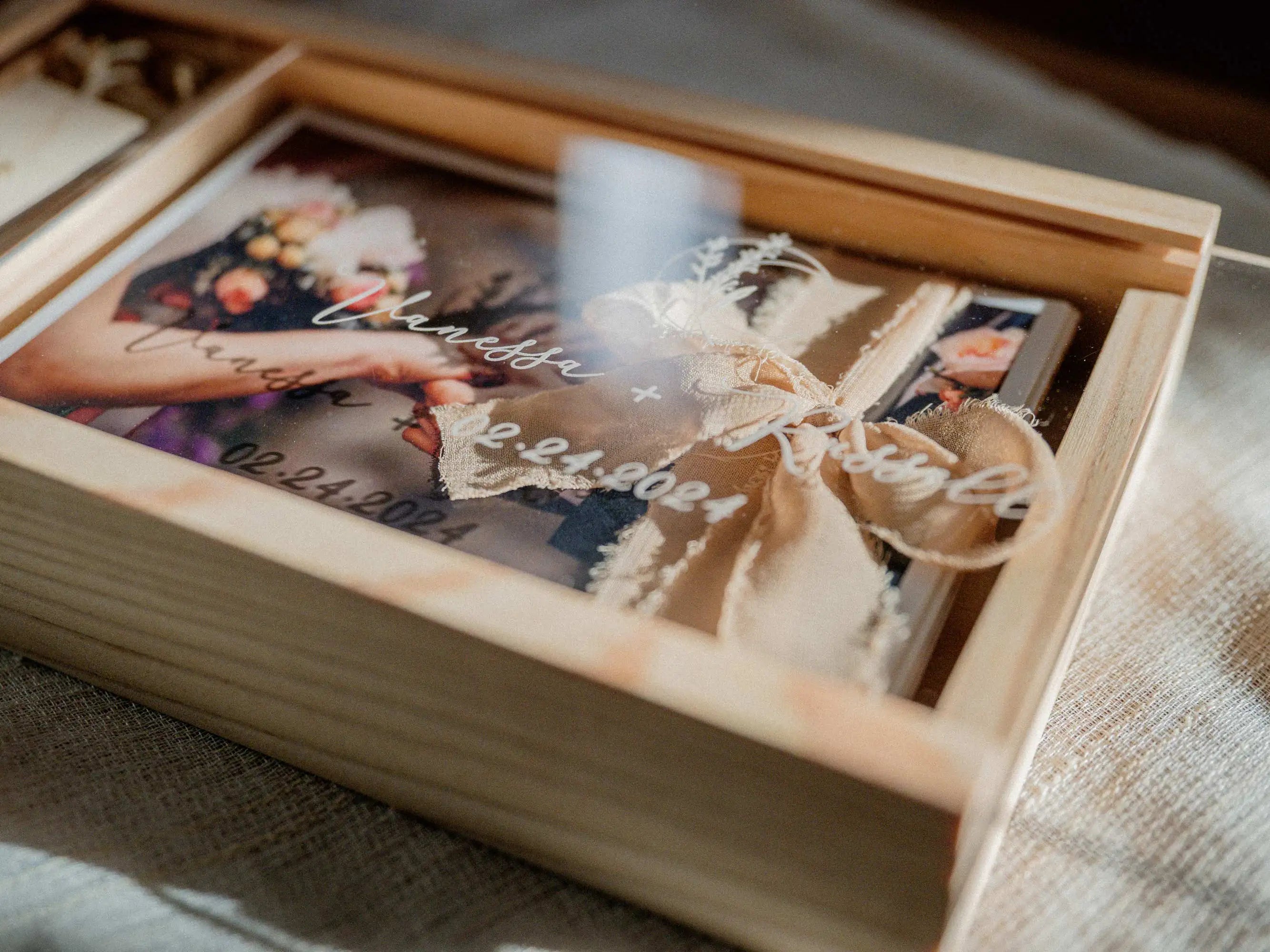 Open maple wooden photo box with prints, ribbon and USB compartment