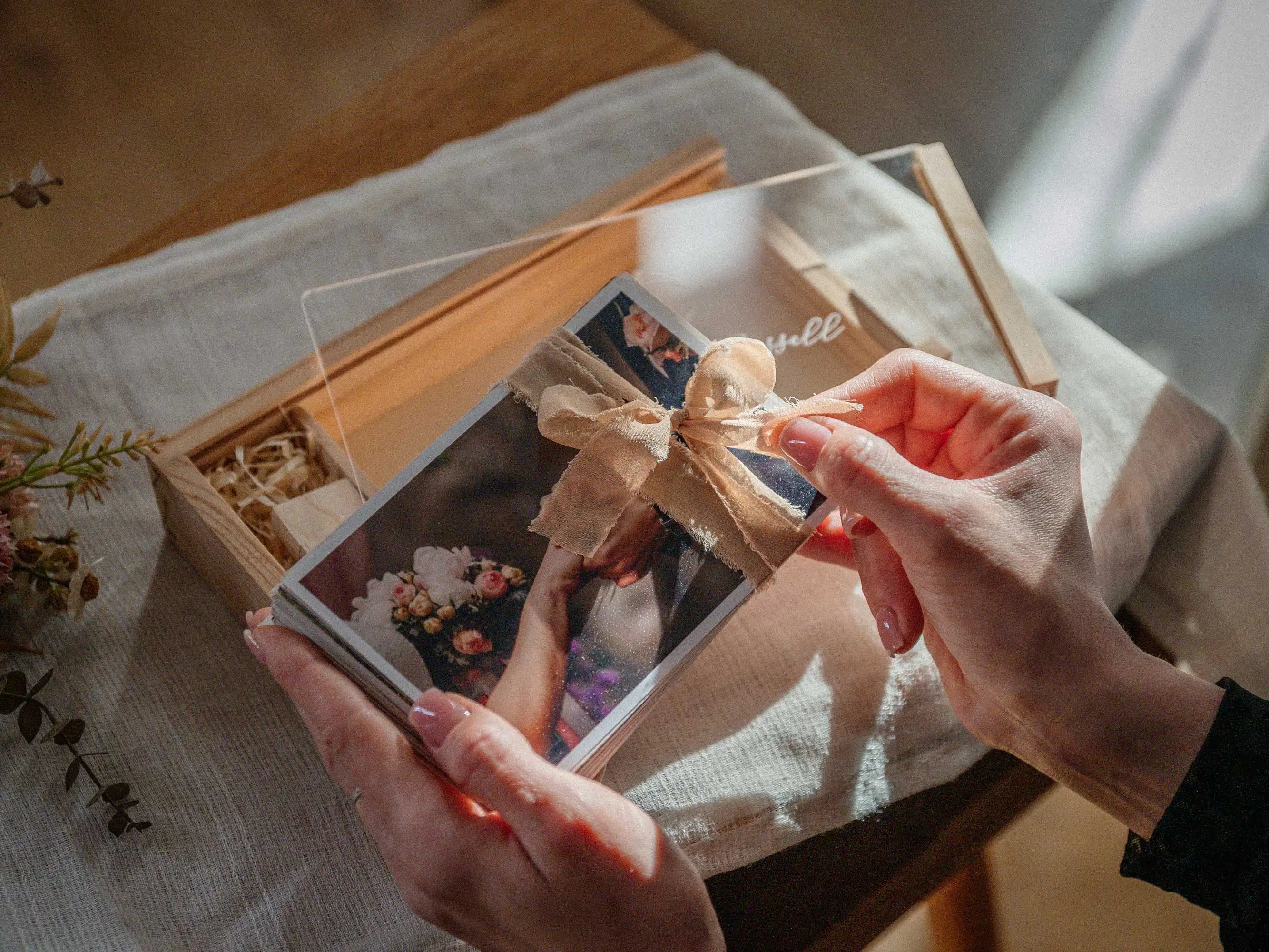 Hands holding wedding photo prints from wooden photo box