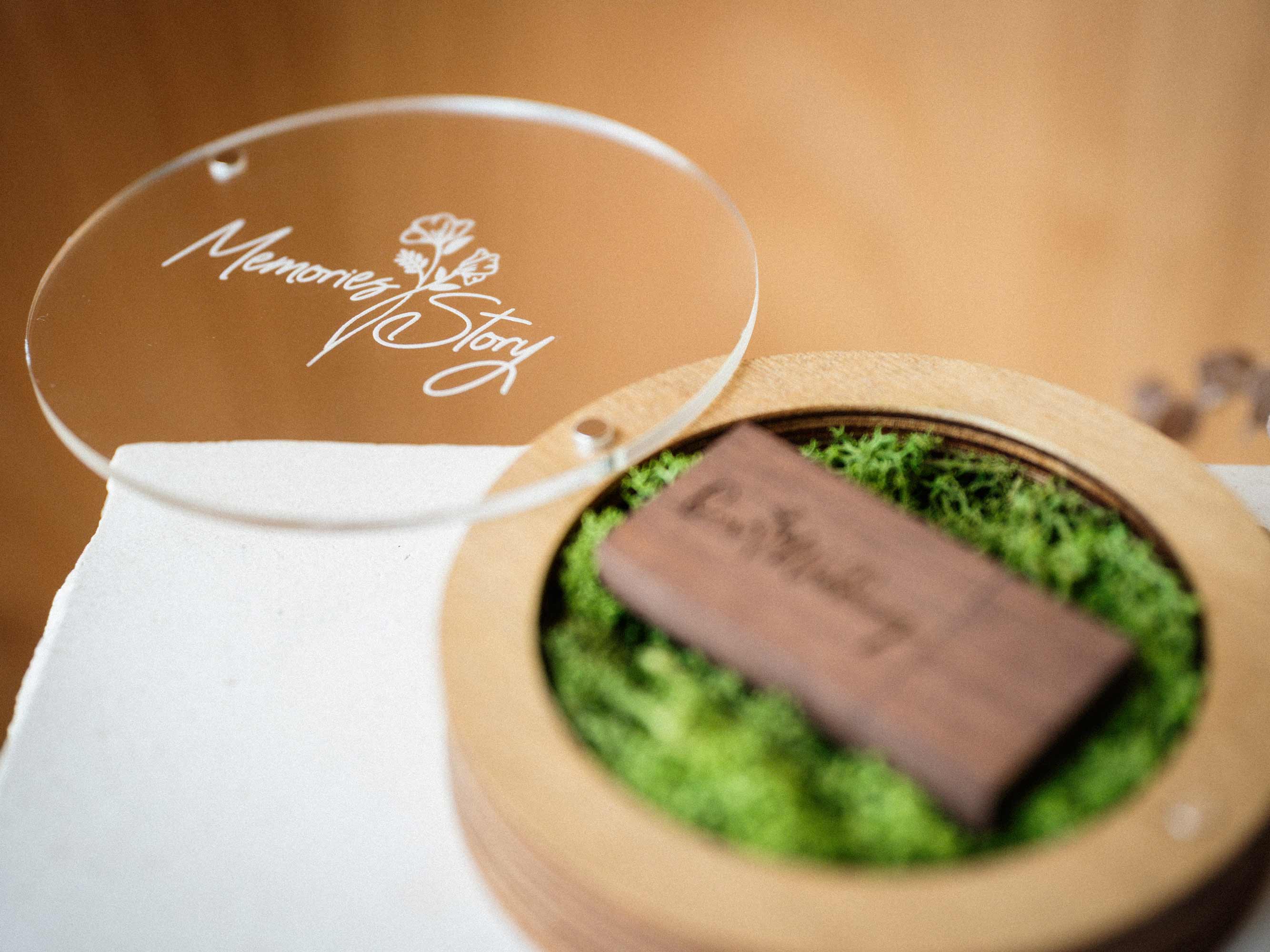 Open Gold Oak USB box with personalized acrylic lid and wooden flash drive on moss