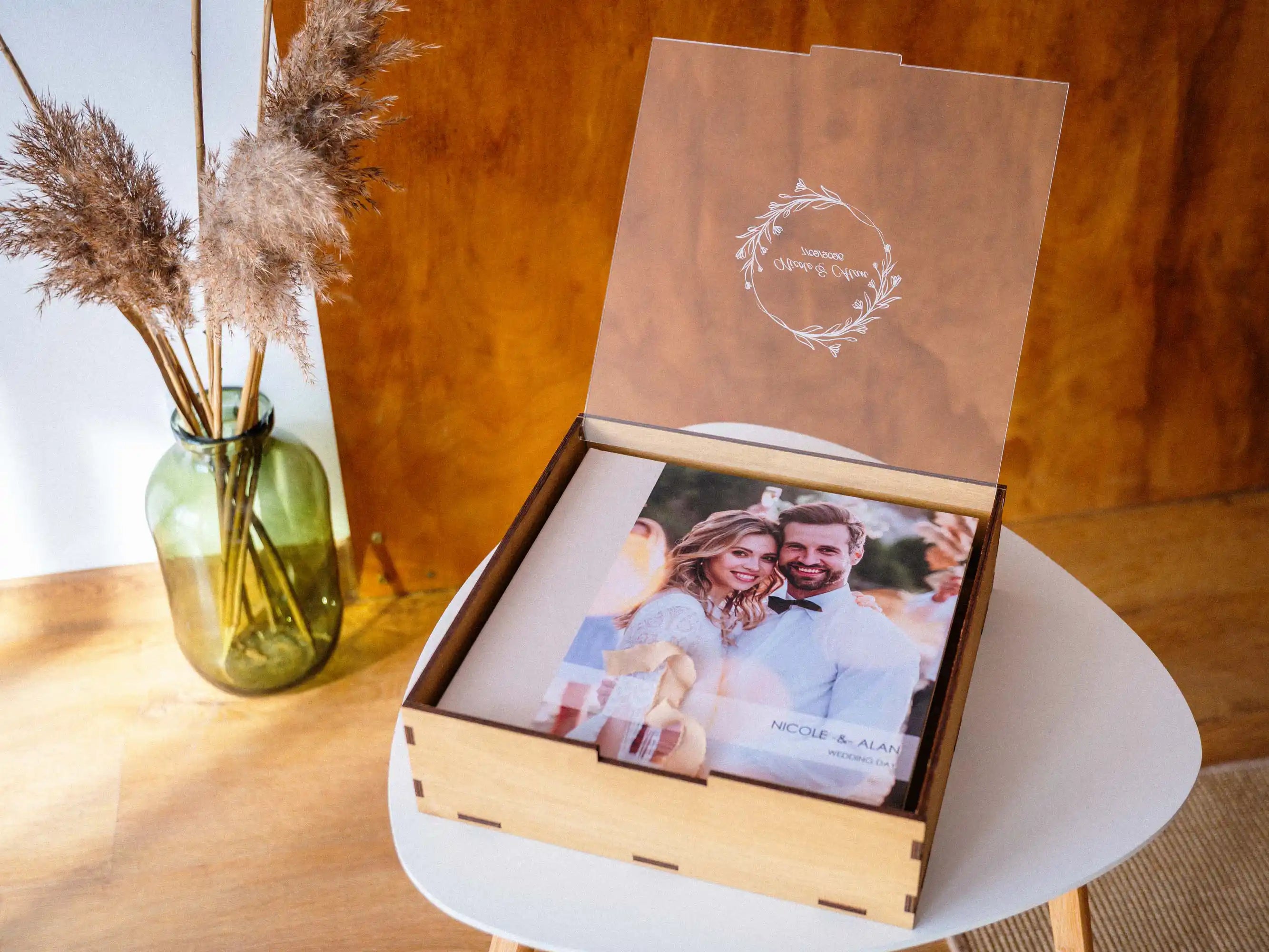 Gold Oak wedding album box with engraved acrylic lid open on a white table, showing a 12x12 photo album inside