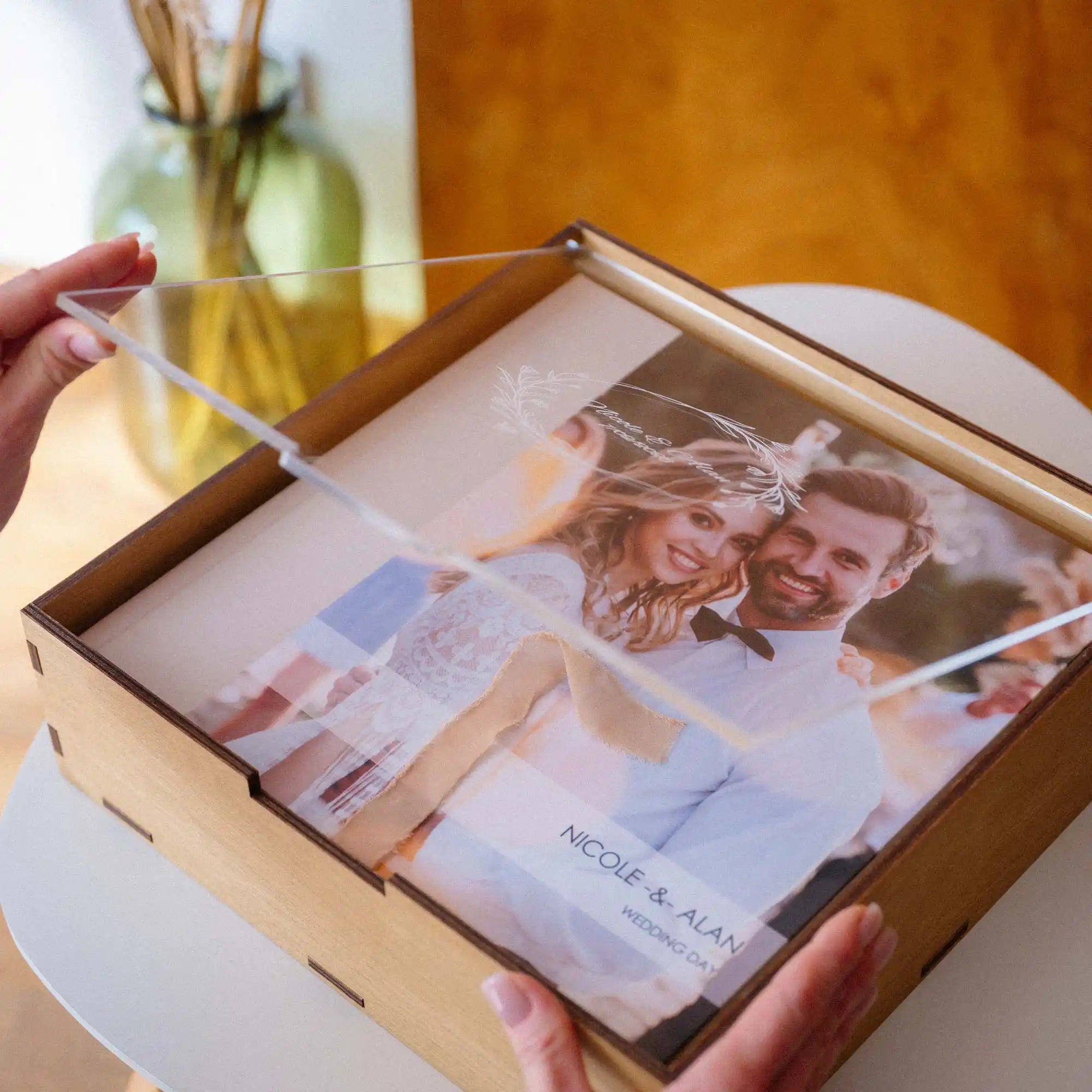 Hands opening a Gold Oak acrylic lid album box with a wedding photo album inside