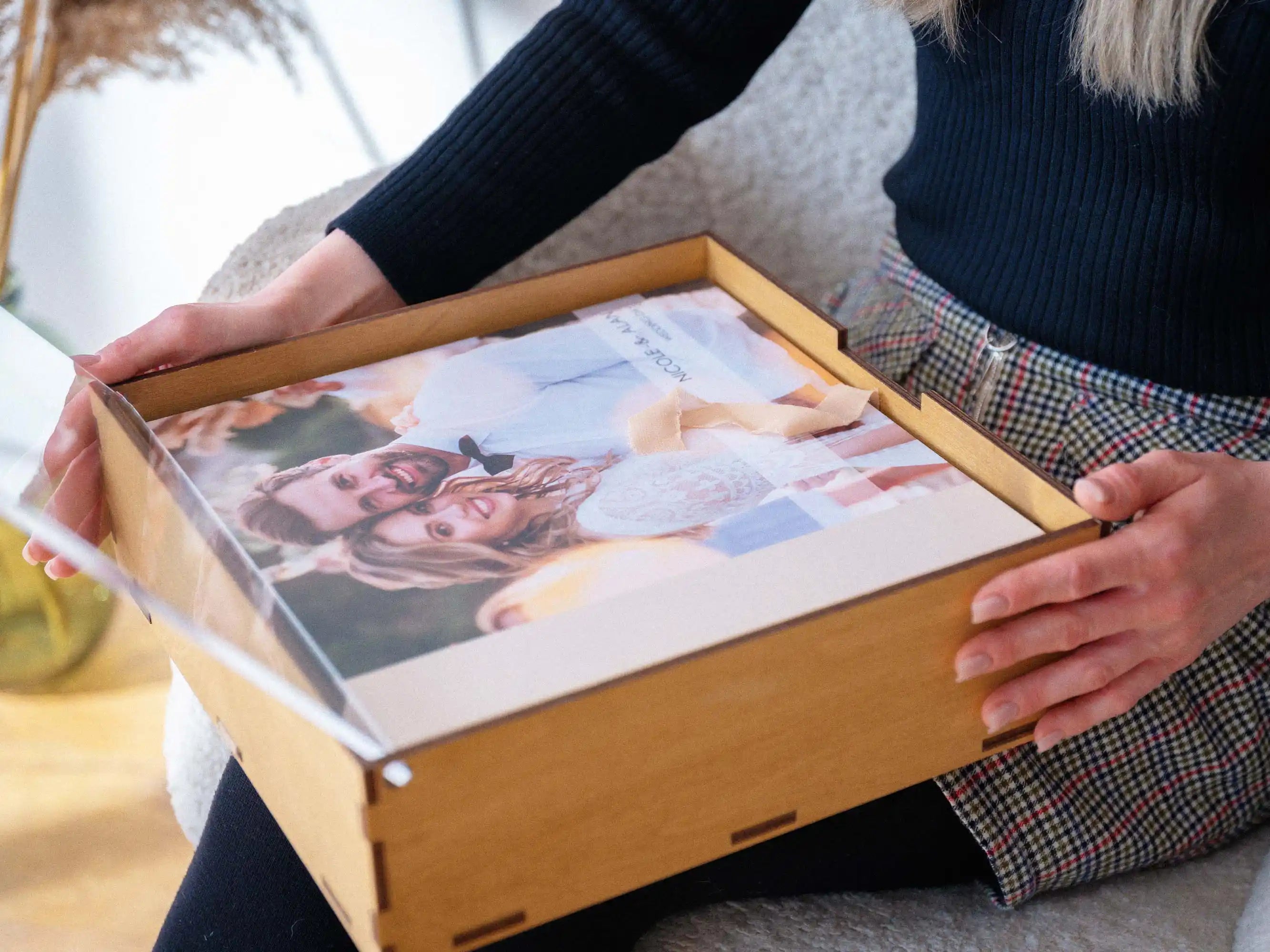 Hands holding an open Gold Oak wedding album box with a printed album inside