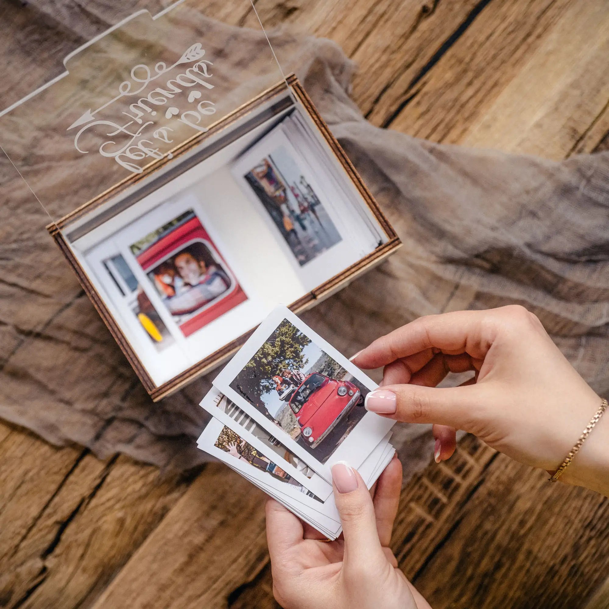 Hand holding Instax Mini prints above a white personalized photo box
