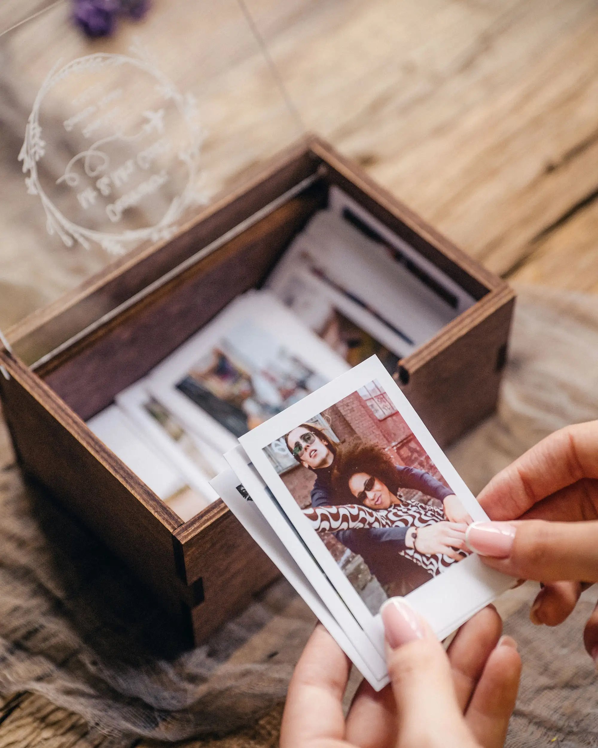 Hand taking an Instax Mini print from a wooden photo storage box