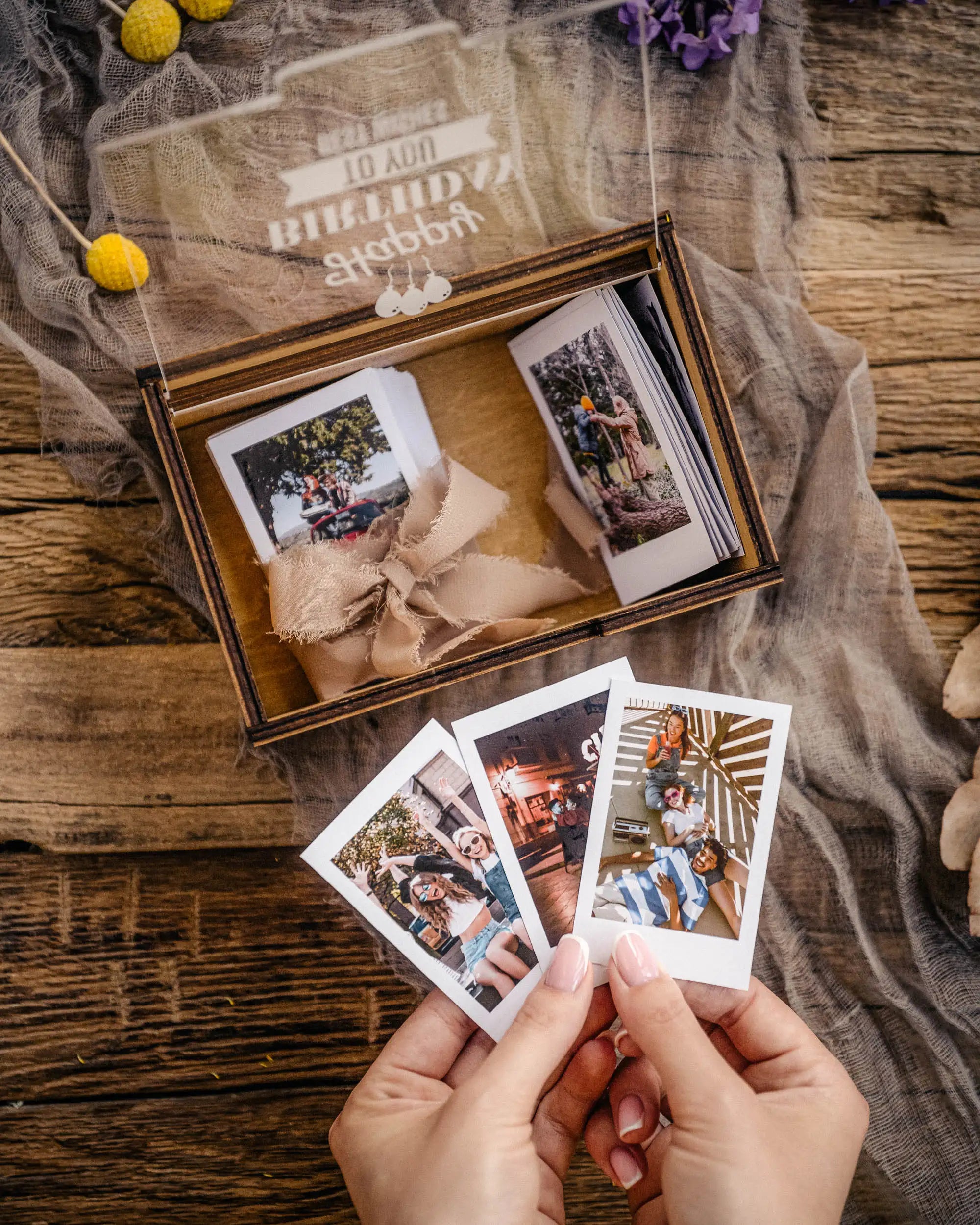 Black personalized Instax Mini photo box with prints and hands holding photos