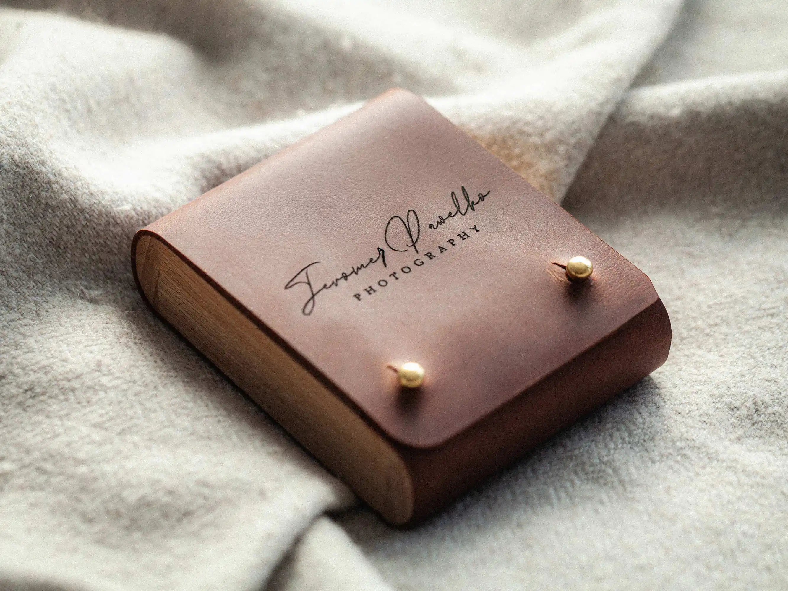 Closed cognac leather USB box, top view showing brass studs and engraving