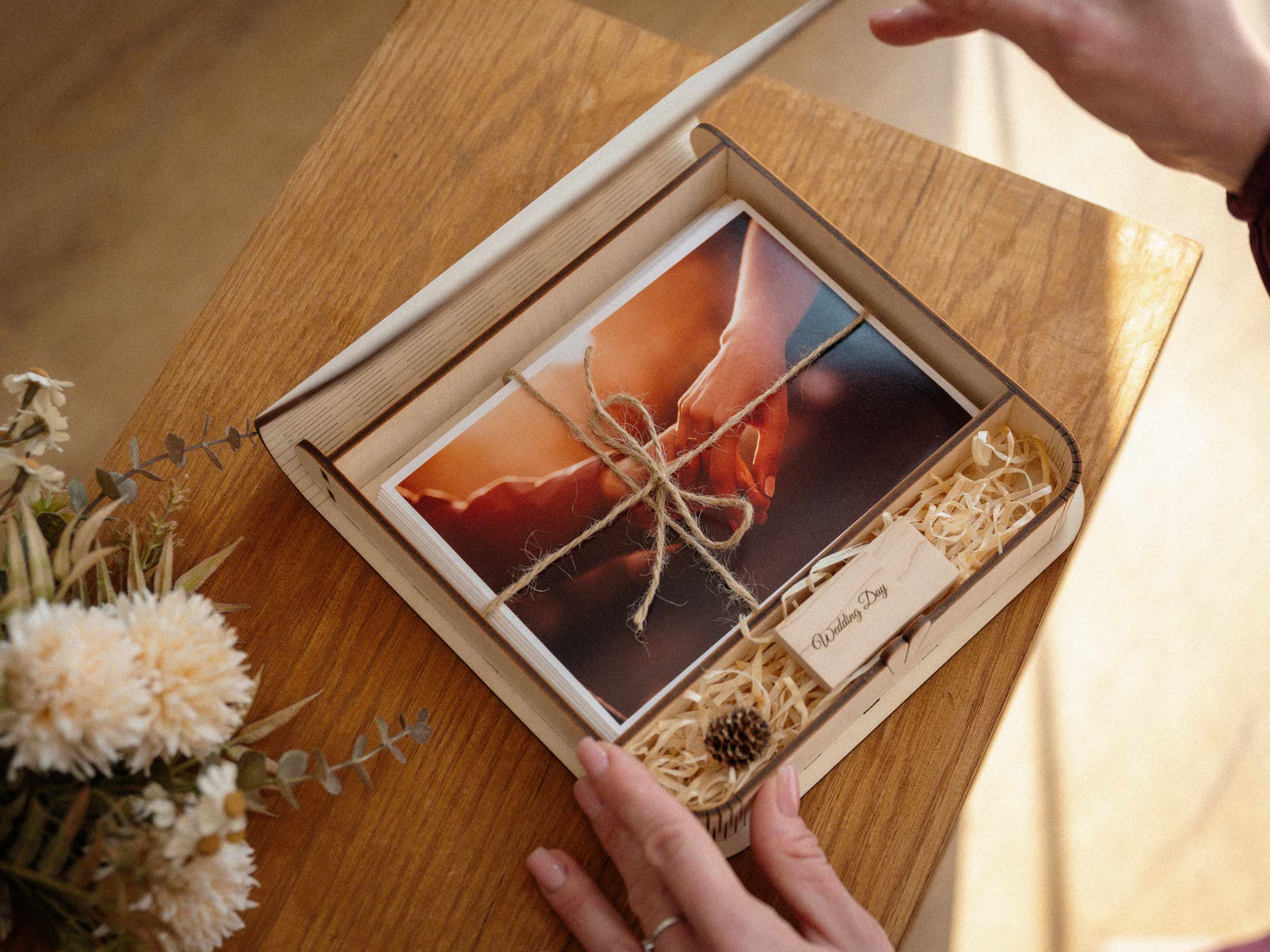 Top view of open maple wedding photo box with USB and printed wedding photos