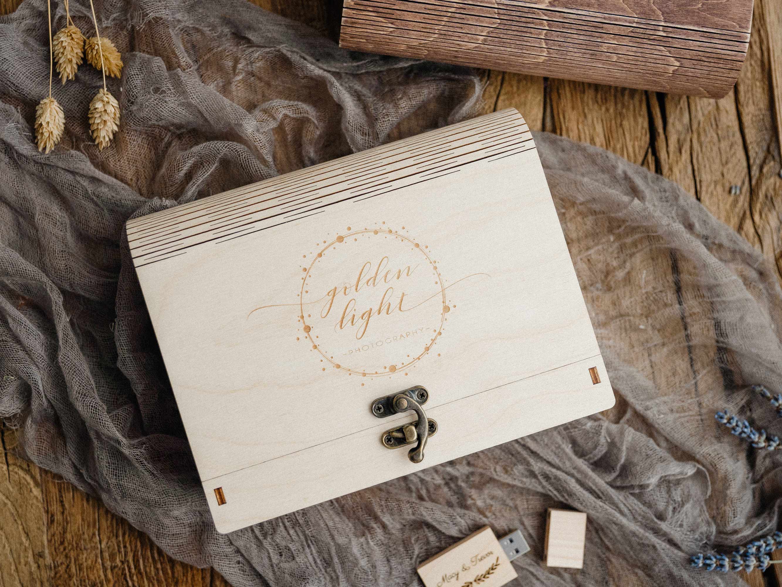 Closed maple wedding photo box with engraved lid and wooden USB, styled flat lay