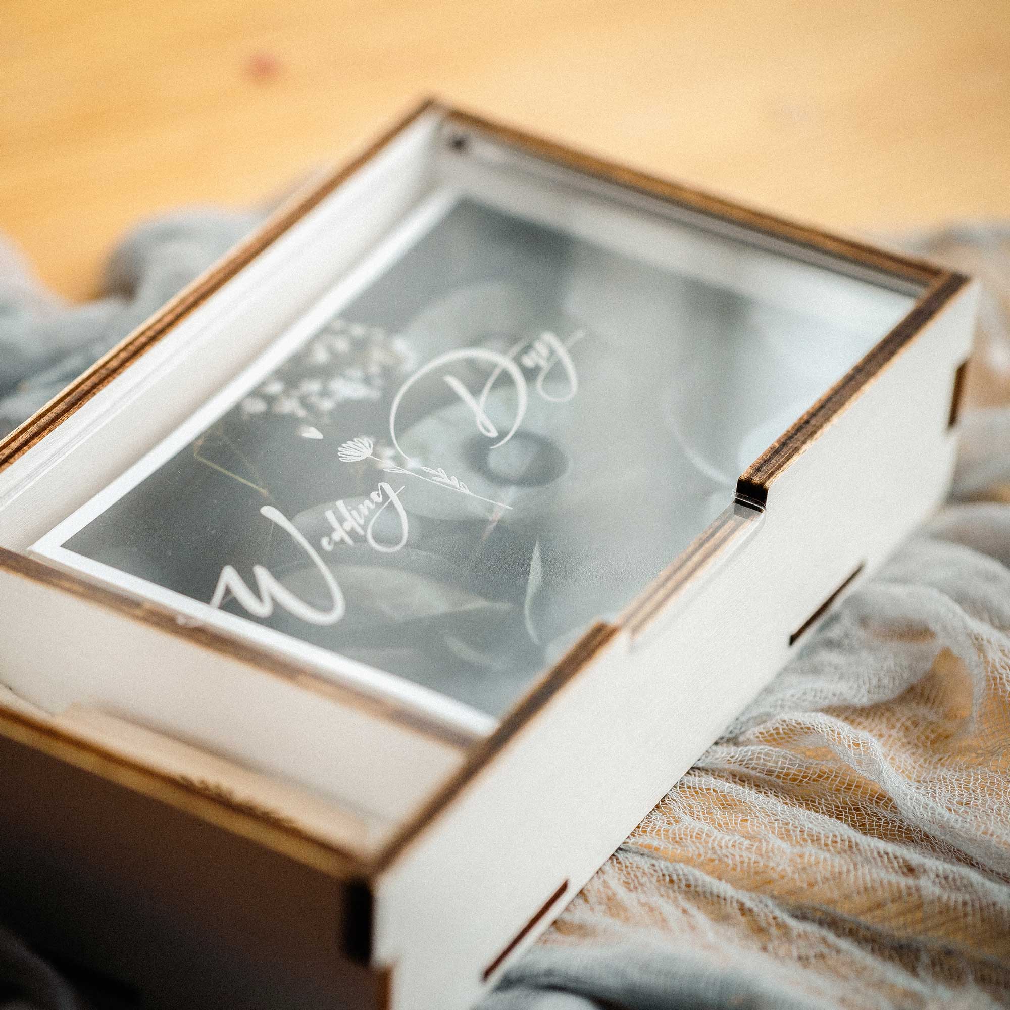 White wooden wedding photo box with engraved acrylic lid on fabric background