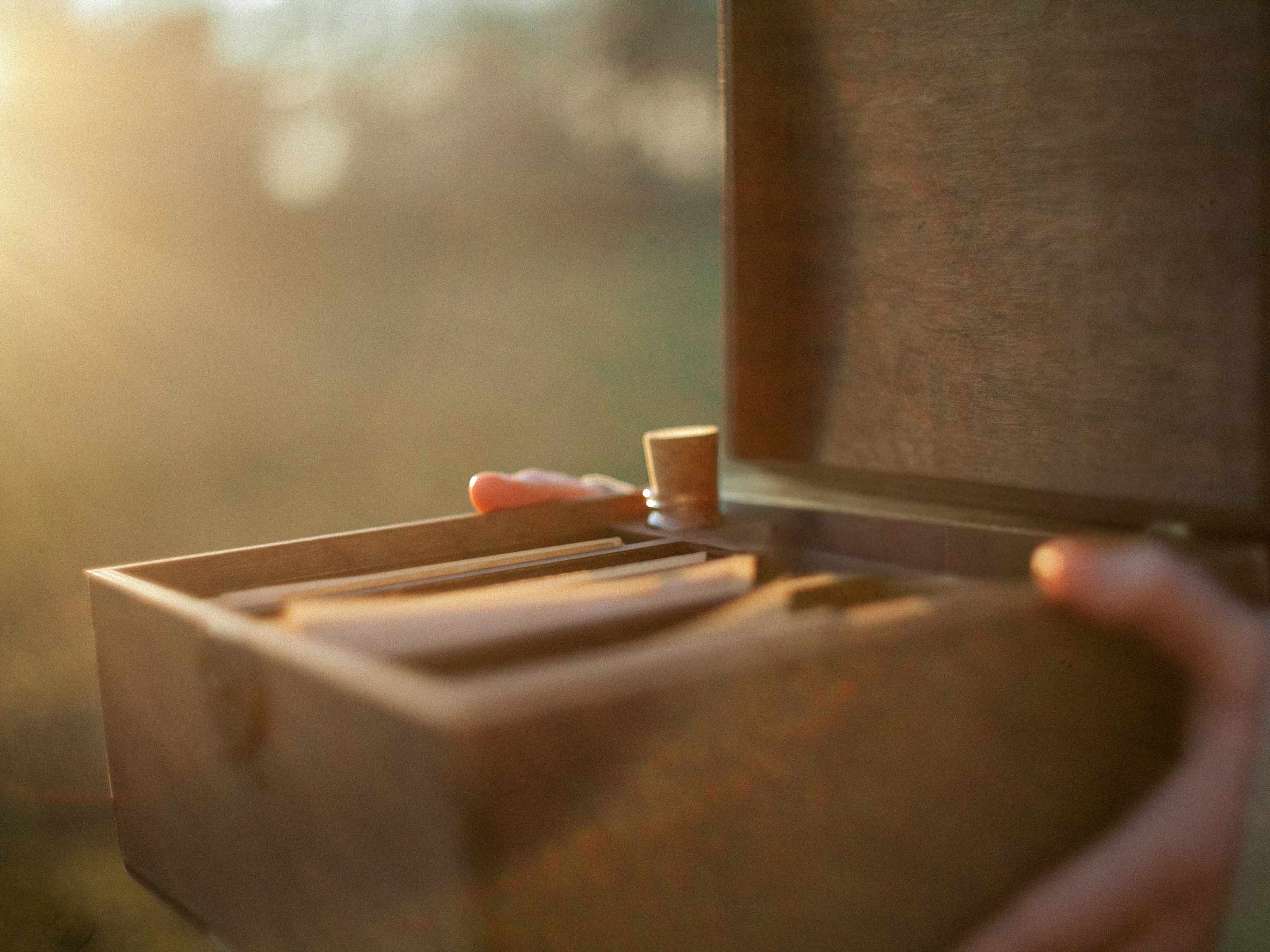 Wooden family photo box being opened with photos inside in warm light