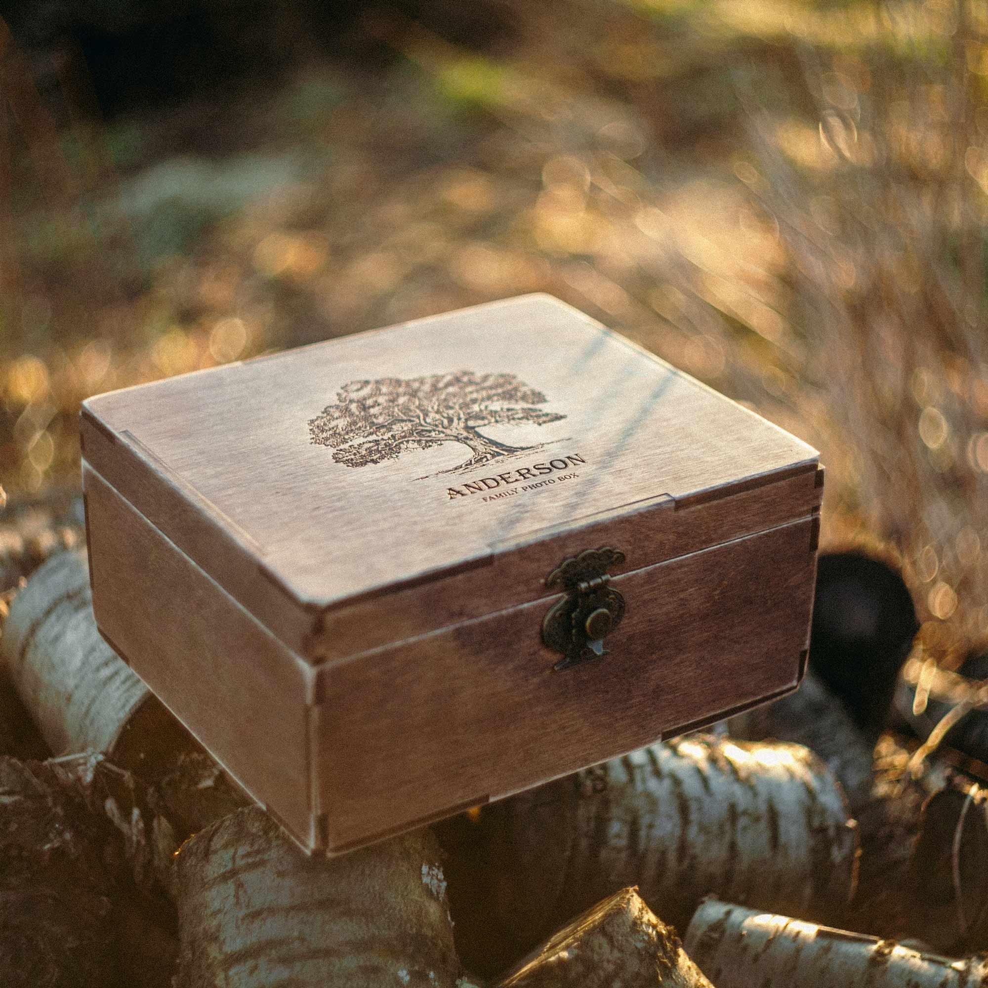 Closed personalized family photo box displayed outdoors on birch logs