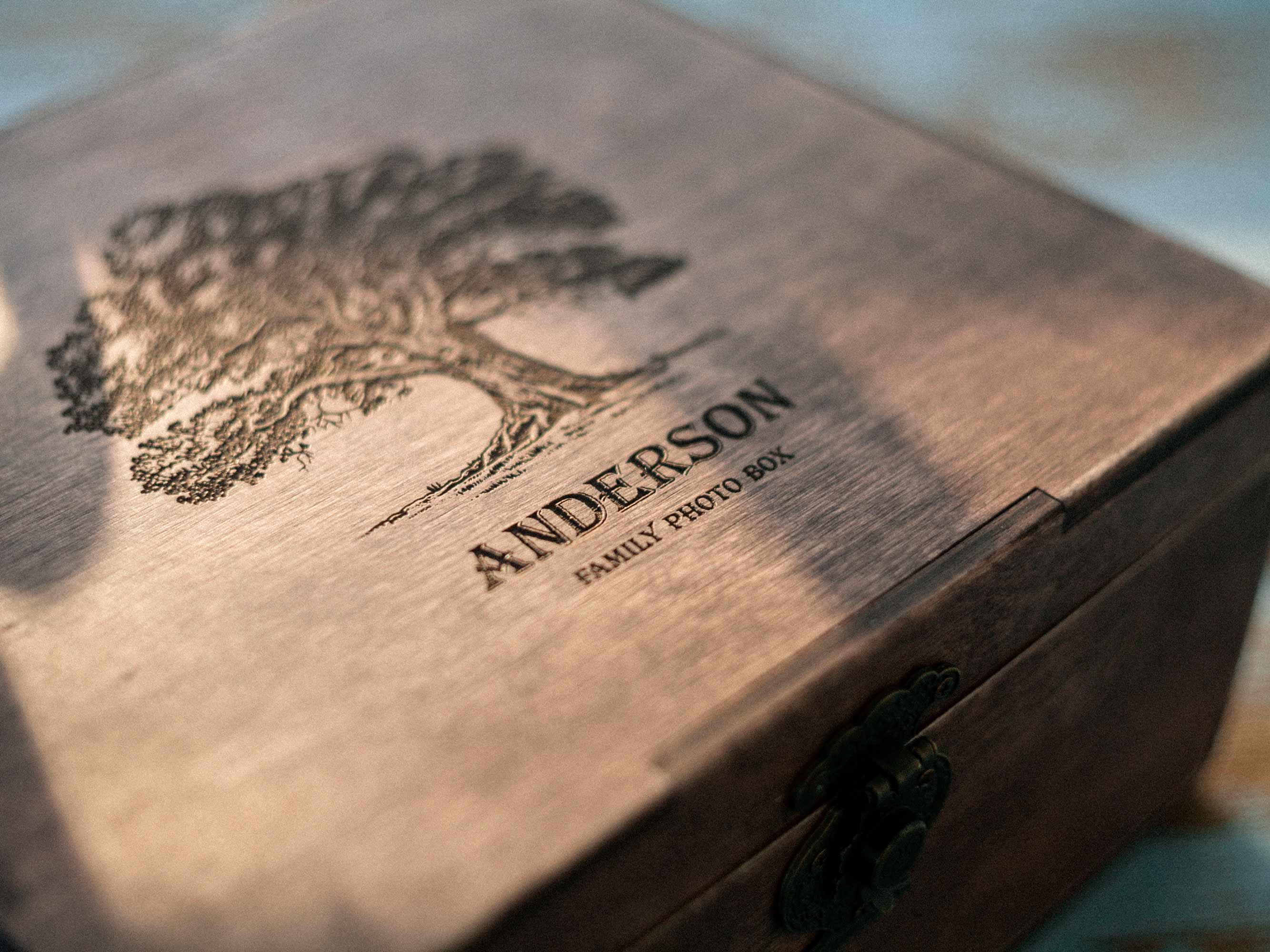 Close-up of engraved tree and family name on wooden photo box lid