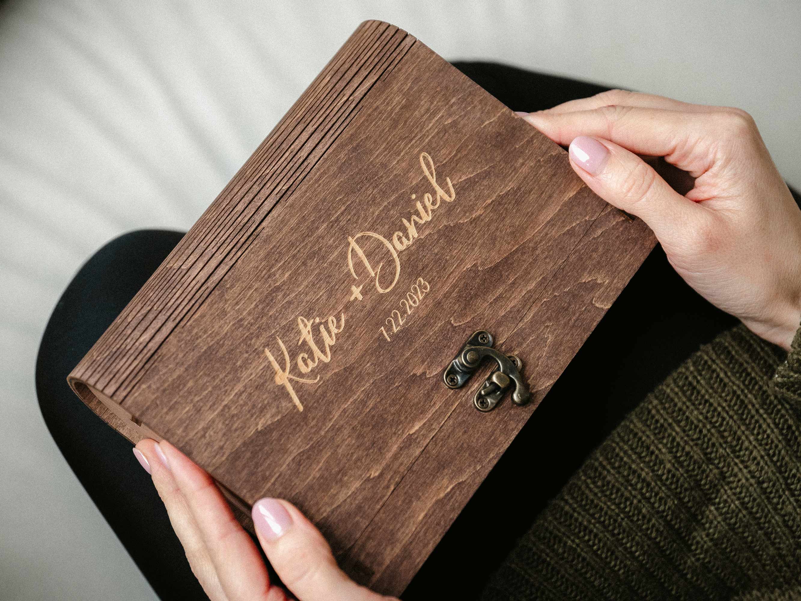 Open walnut photo box in hands, top view with wedding photo inside