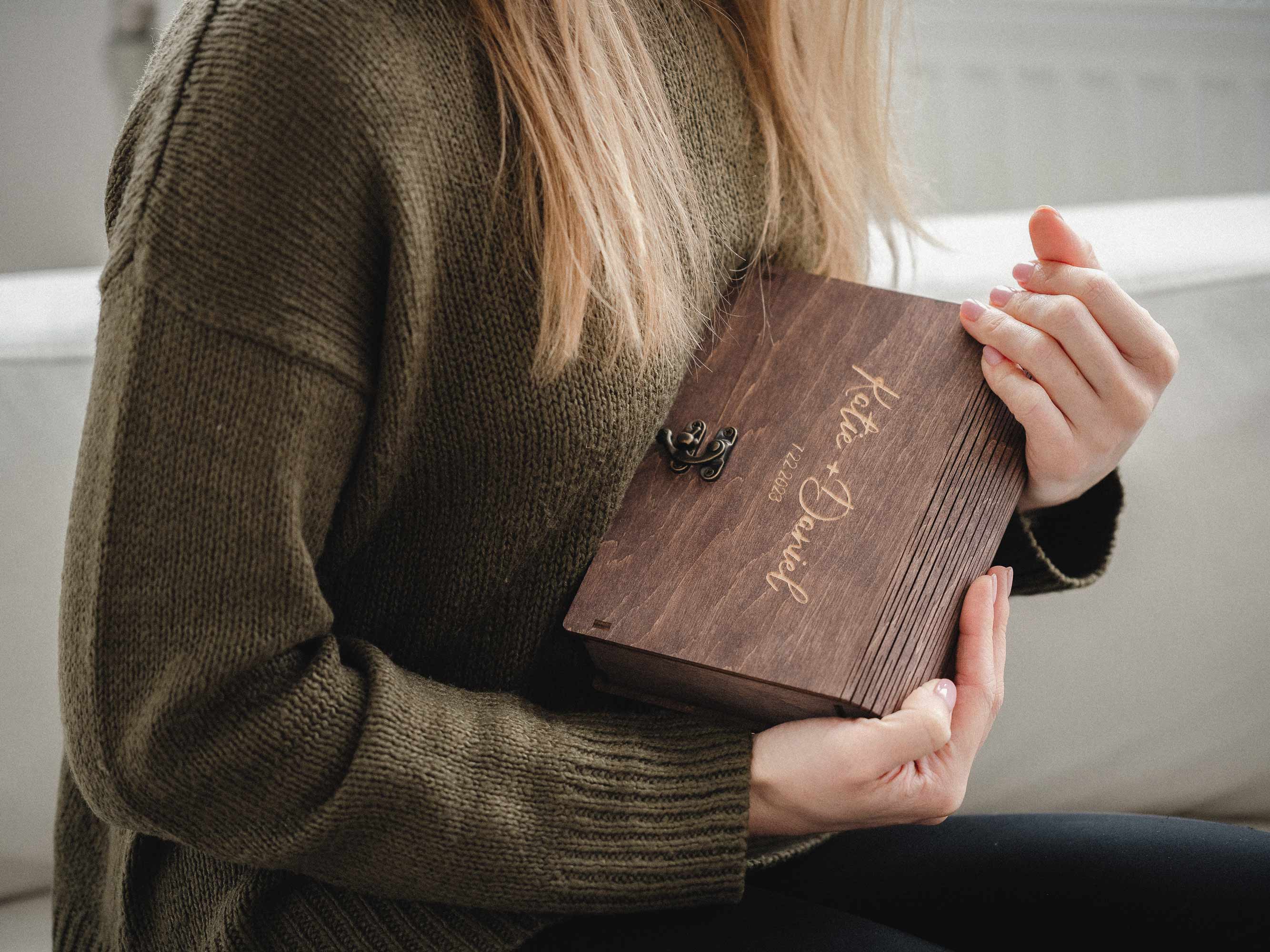 Hand holding wedding photo stack over an open wooden keepsake box