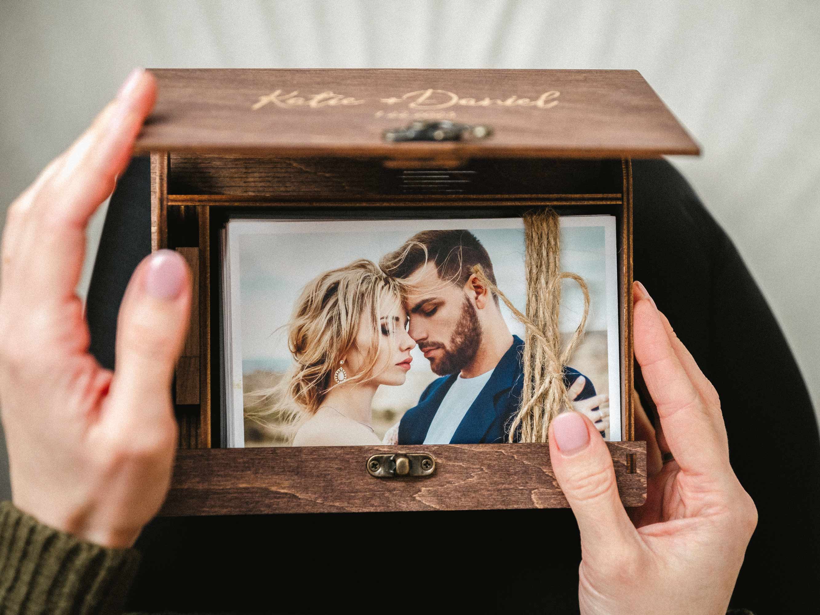 Open walnut photo box held in hands showing a wedding portrait print