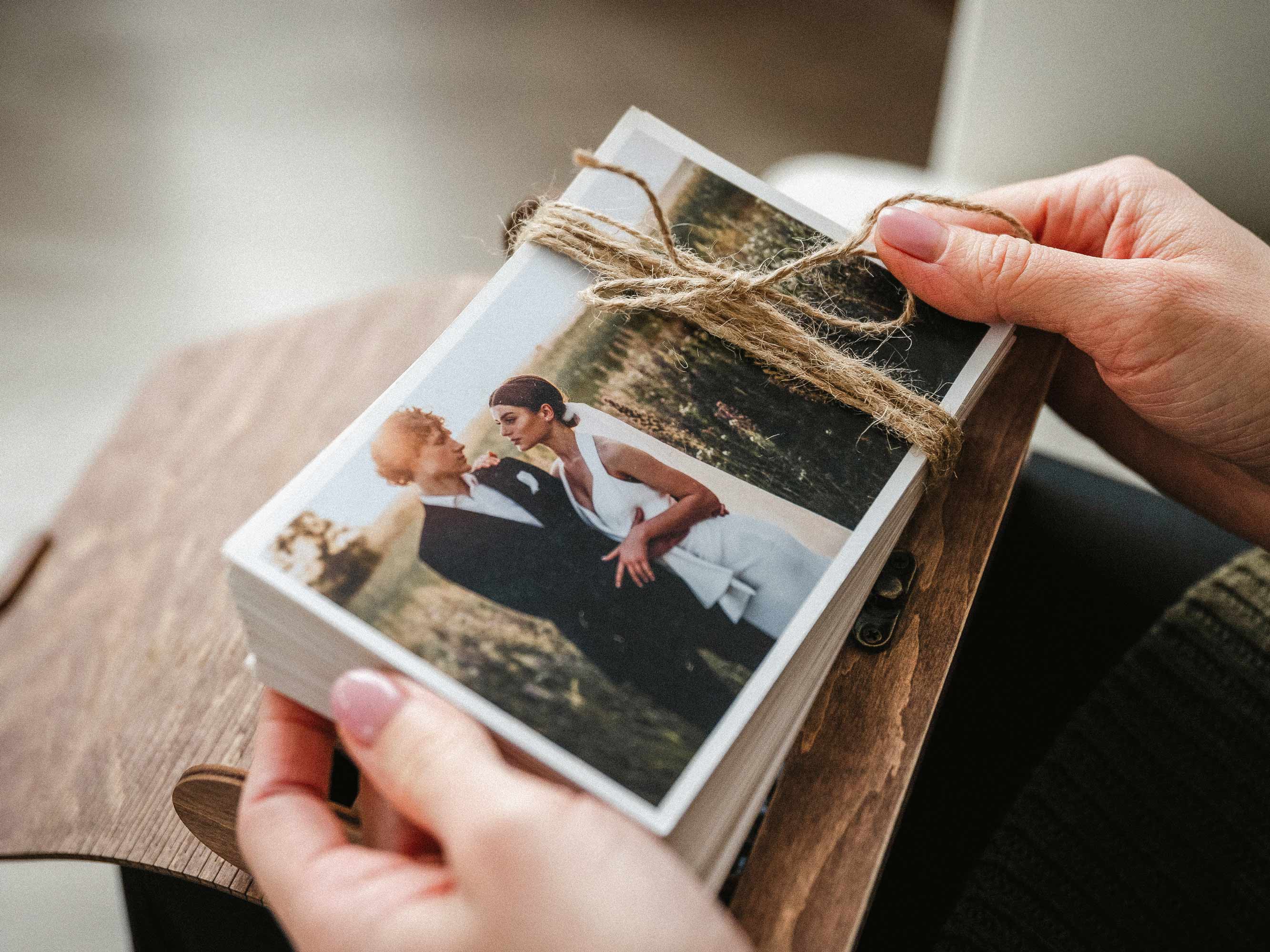 Hands tying a stack of wedding prints for walnut photo box presentation