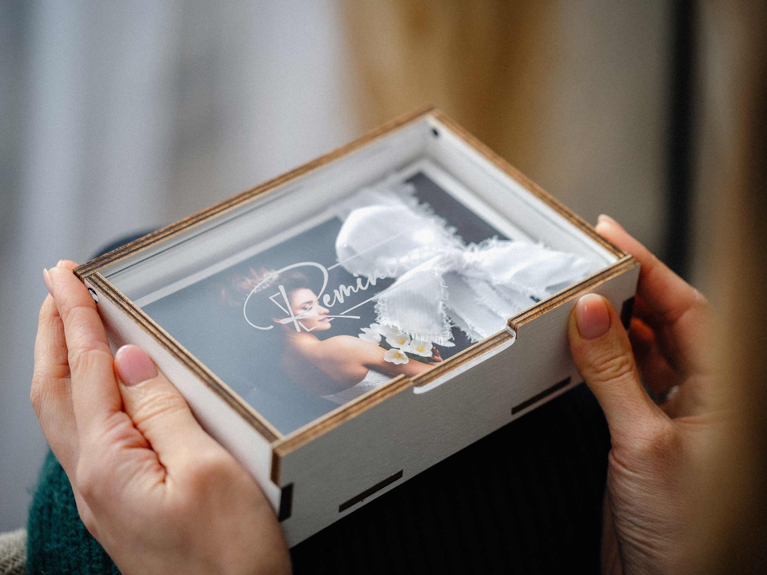 Close view of white photo box with clear acrylic lid and wedding photo stack.