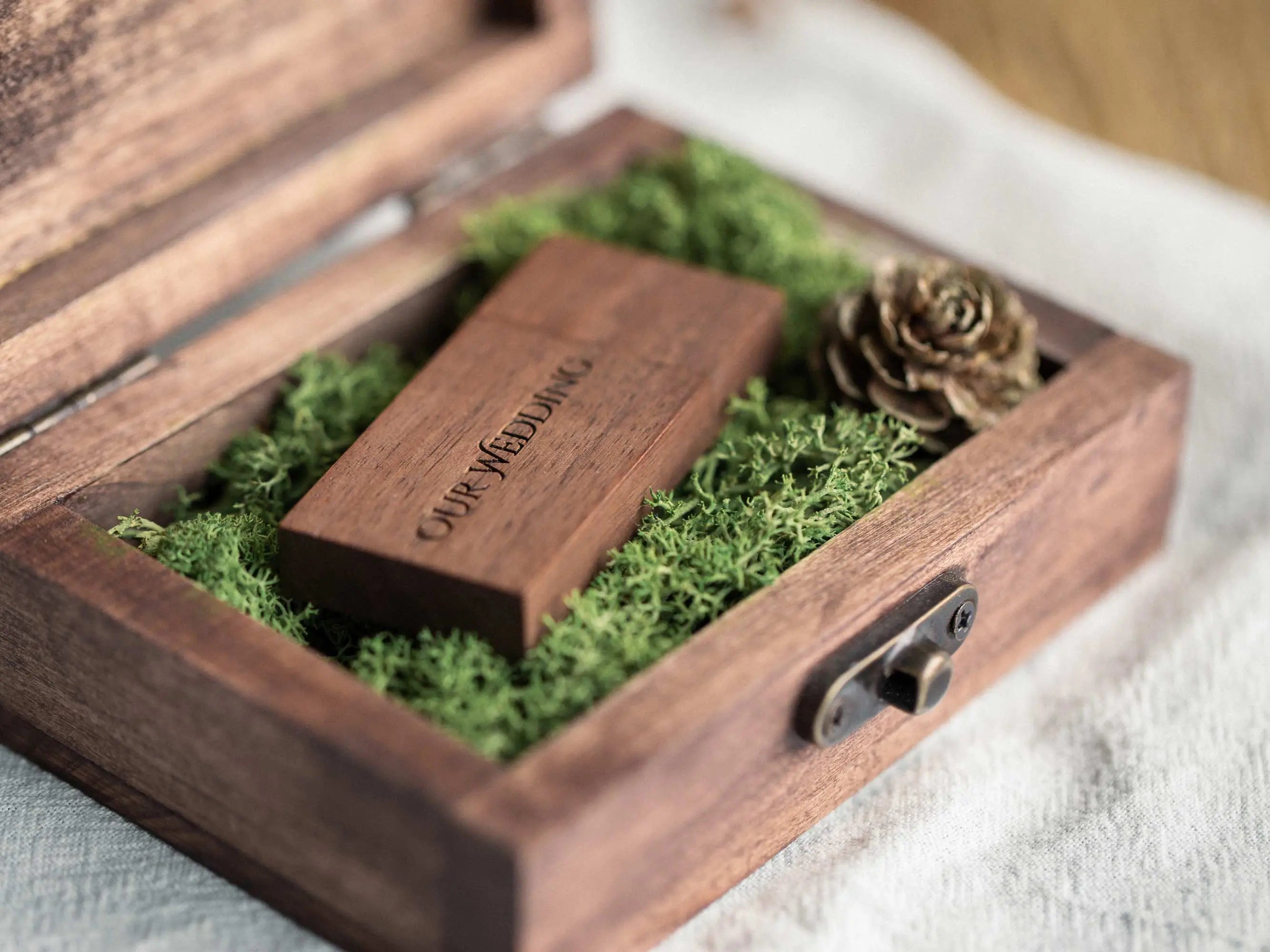 Angled top view of an open wooden USB box with moss lining and USB drive inside.