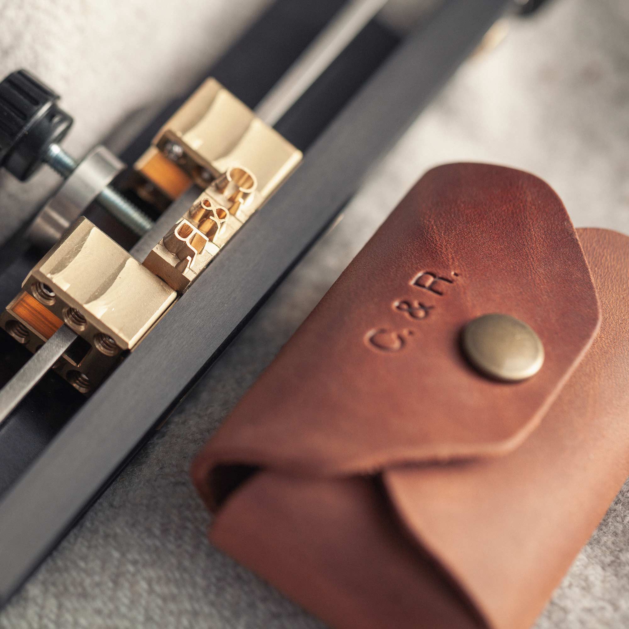 Hot stamping machine embossing initials on cognac leather USB case