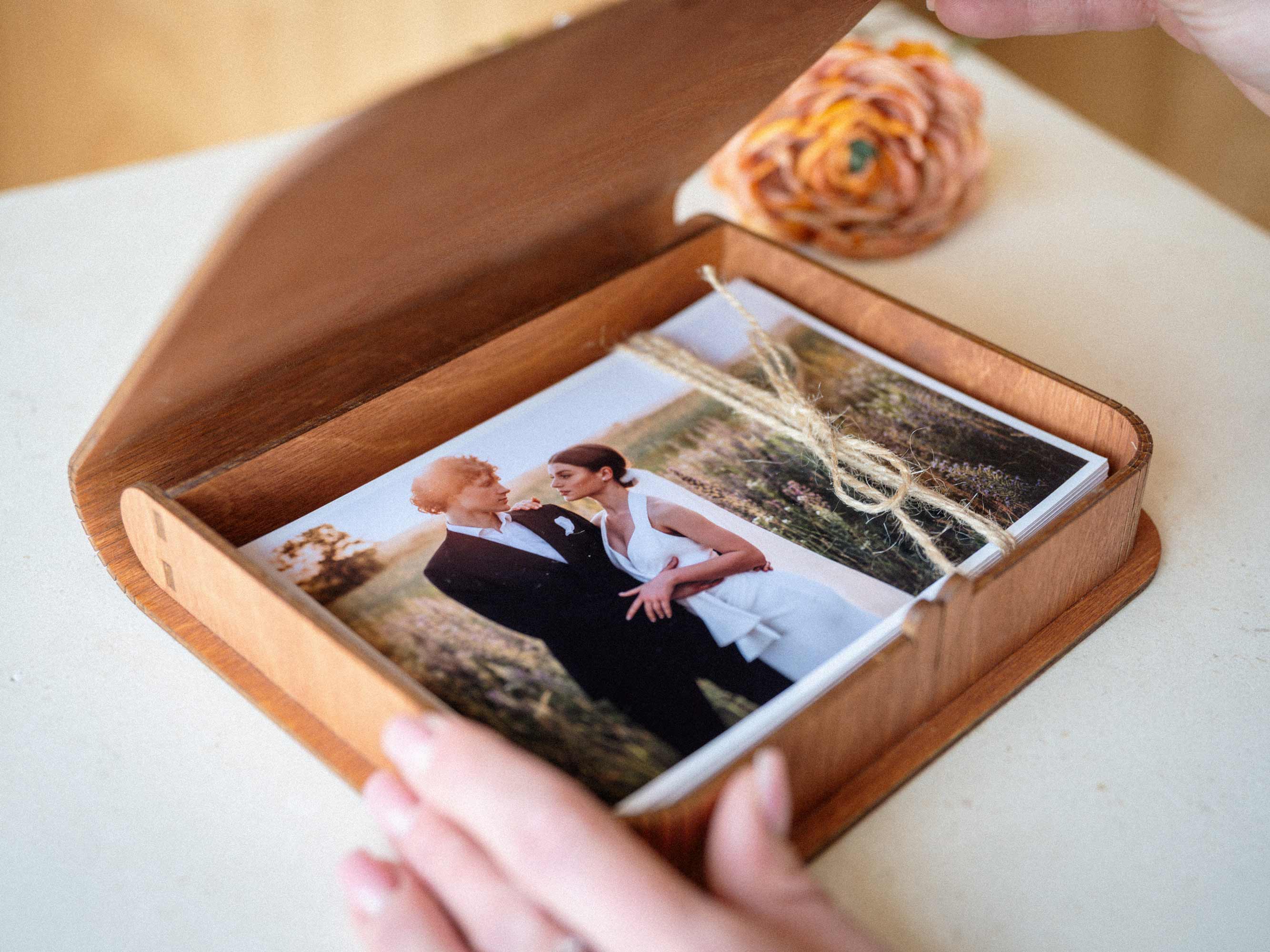 Teak wooden photo storage box open with printed photos on table