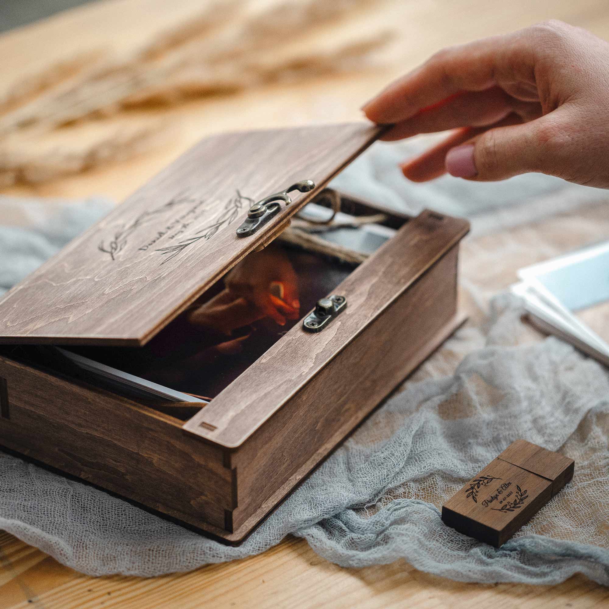 Hand lifting lid to reveal photos inside vintage walnut wooden photo box with clasp