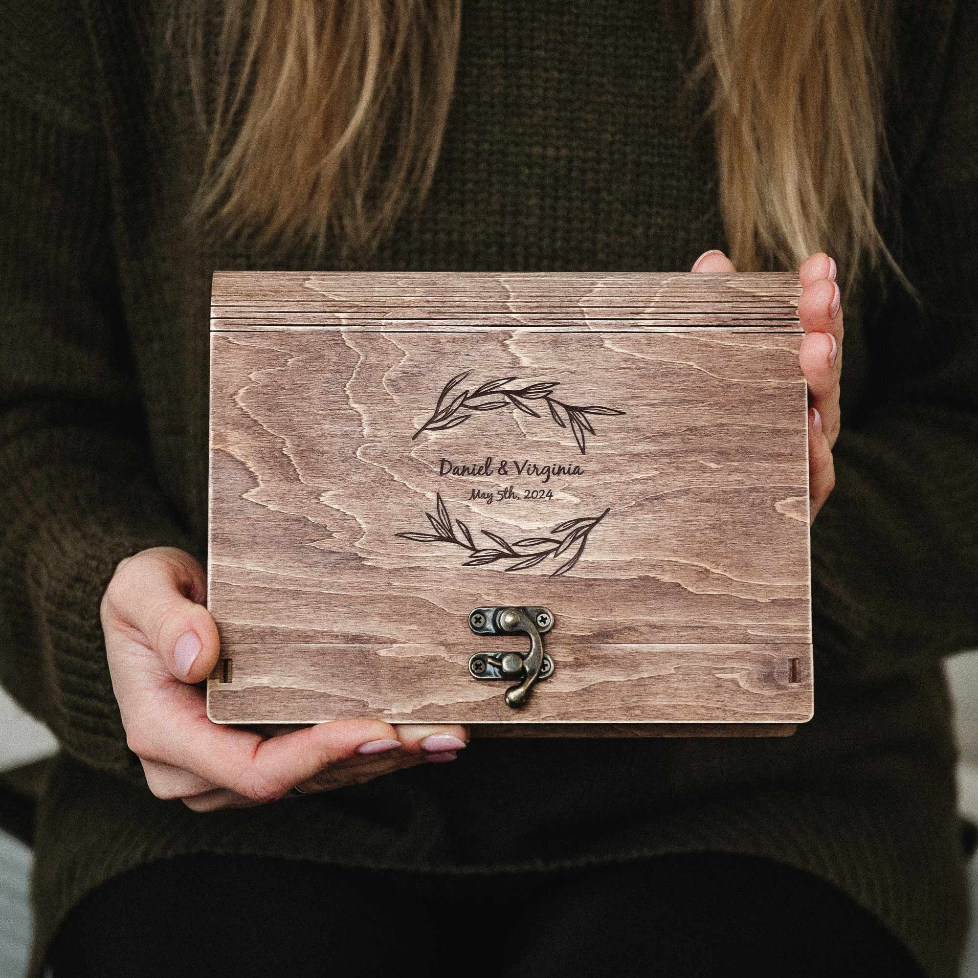 Person holding personalized vintage walnut wedding photo box with engraved design and clasp, front view