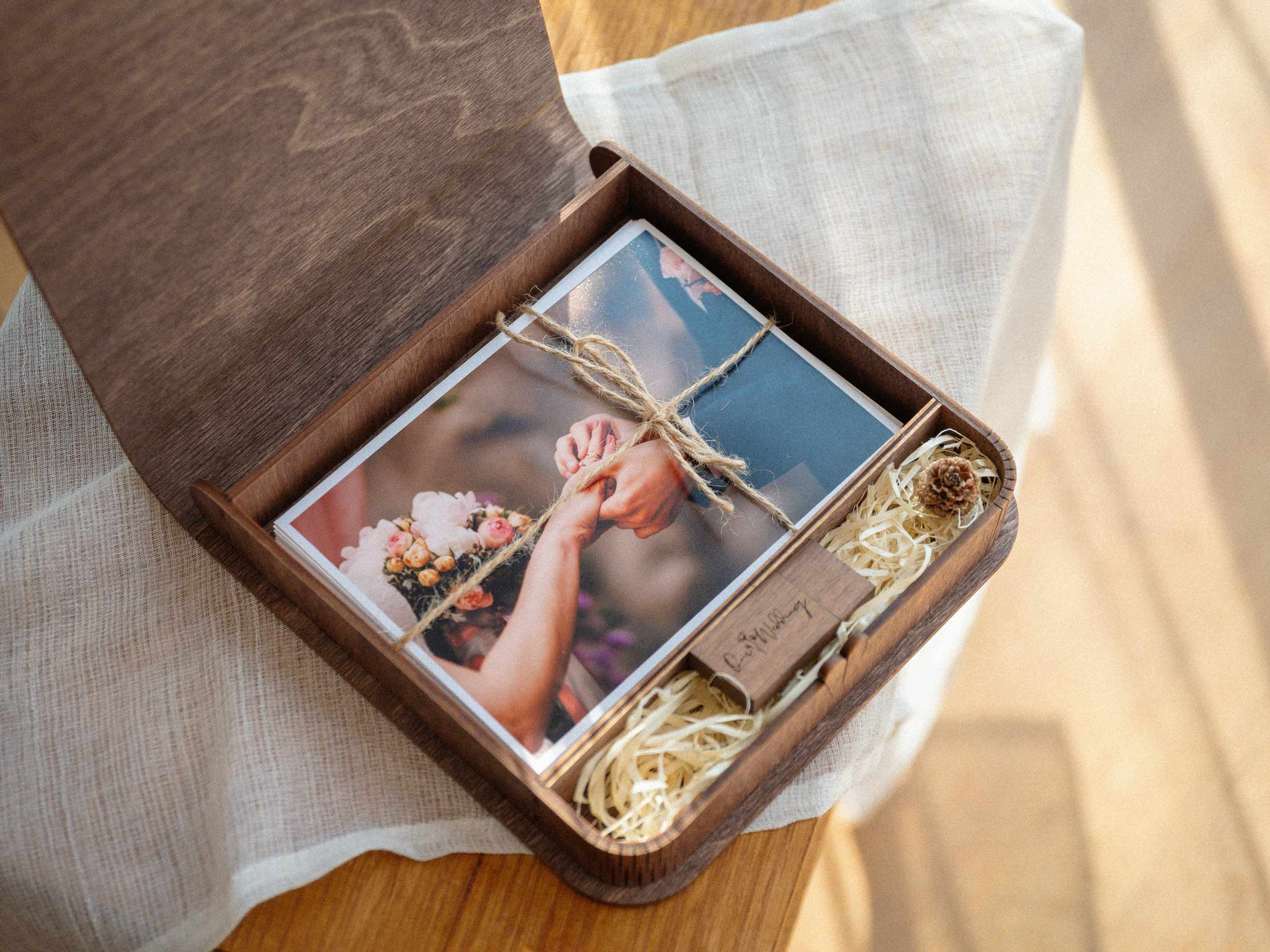Top view of open walnut wooden photo box with USB and printed photos