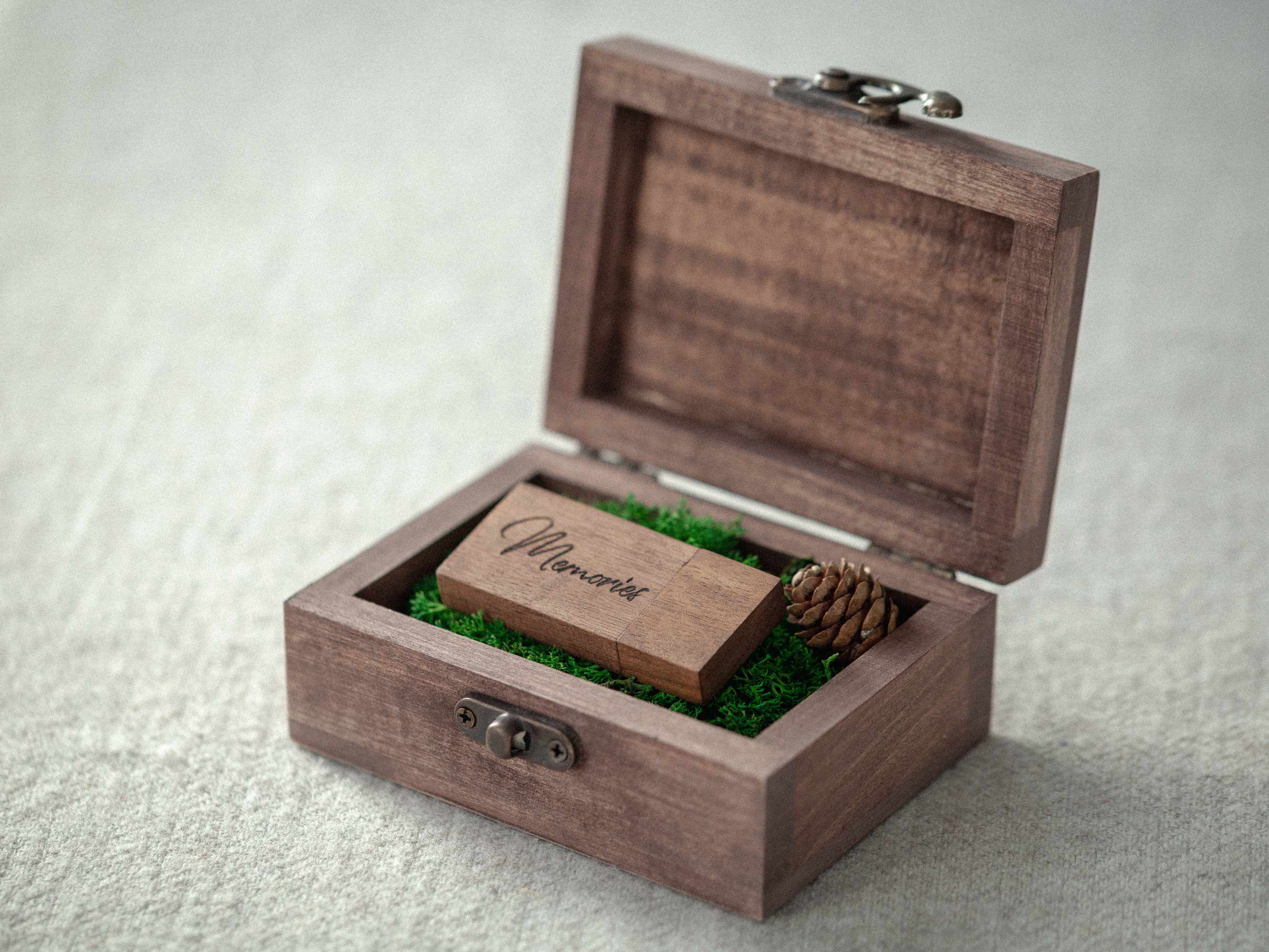 Open walnut wooden USB box with engraved wooden flash drive on neutral fabric