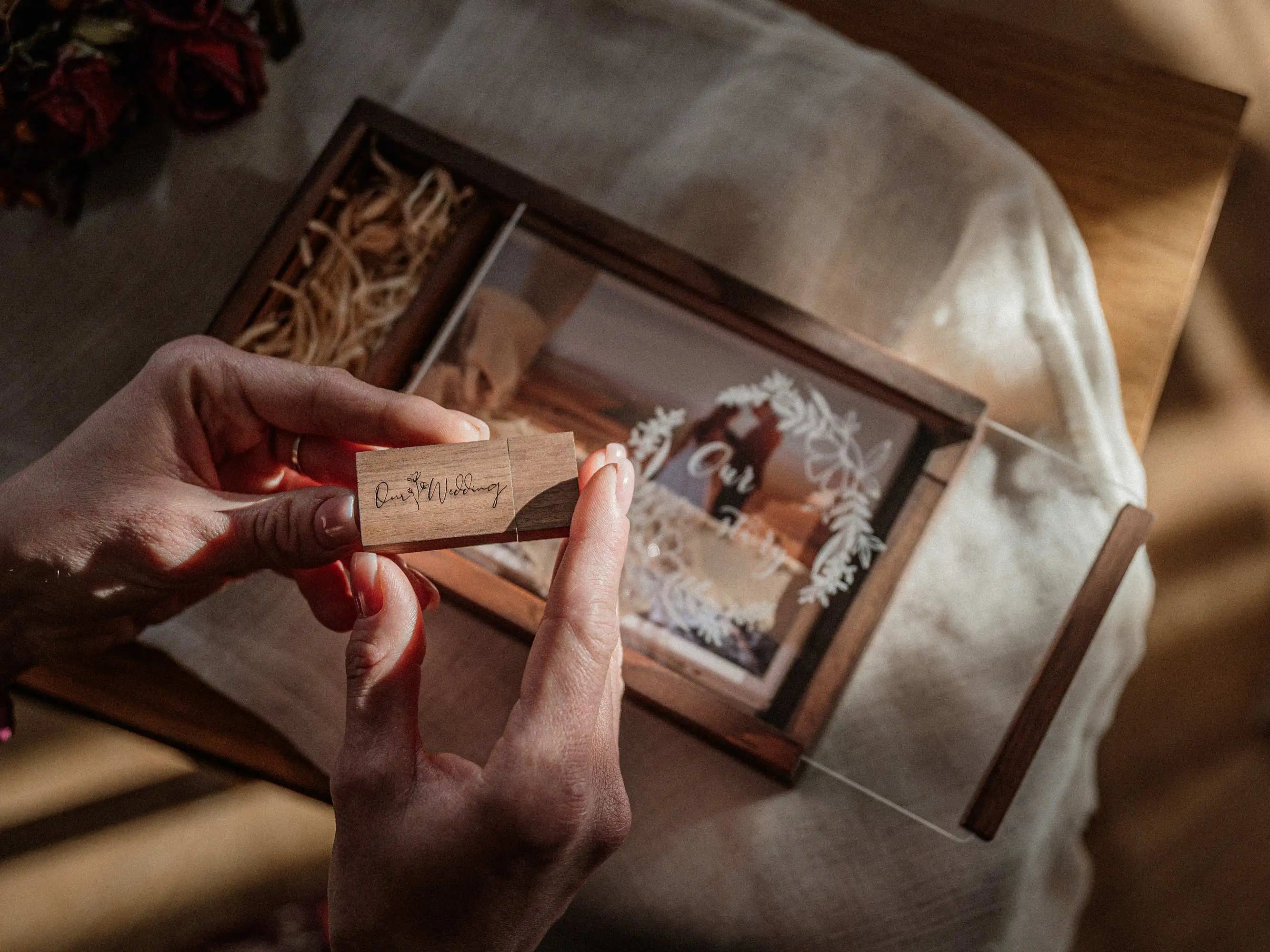 Hands holding wooden USB over personalized wedding photo box with printed photo inside